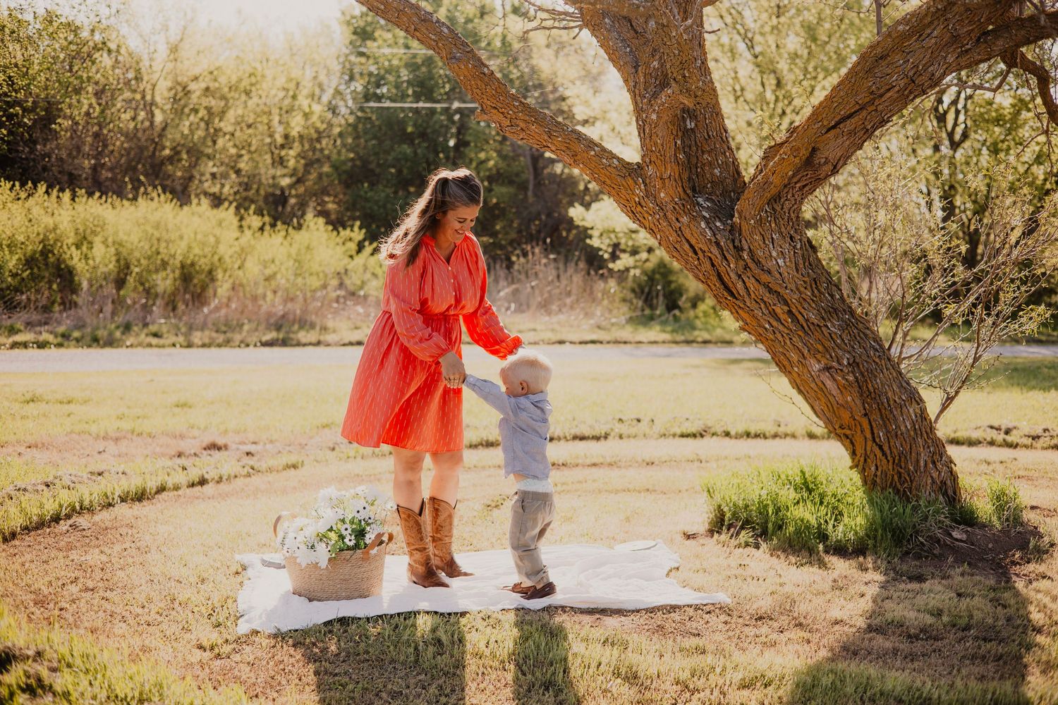 Two people dance together on a blanket under a tree in a sunlit garden setting during a golden afternoon.