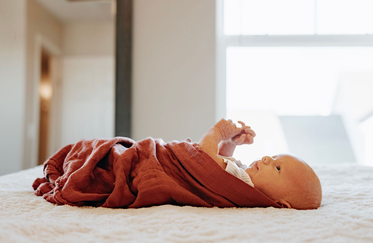 Close-up view of tiny baby feet and hands resting on white bedding.