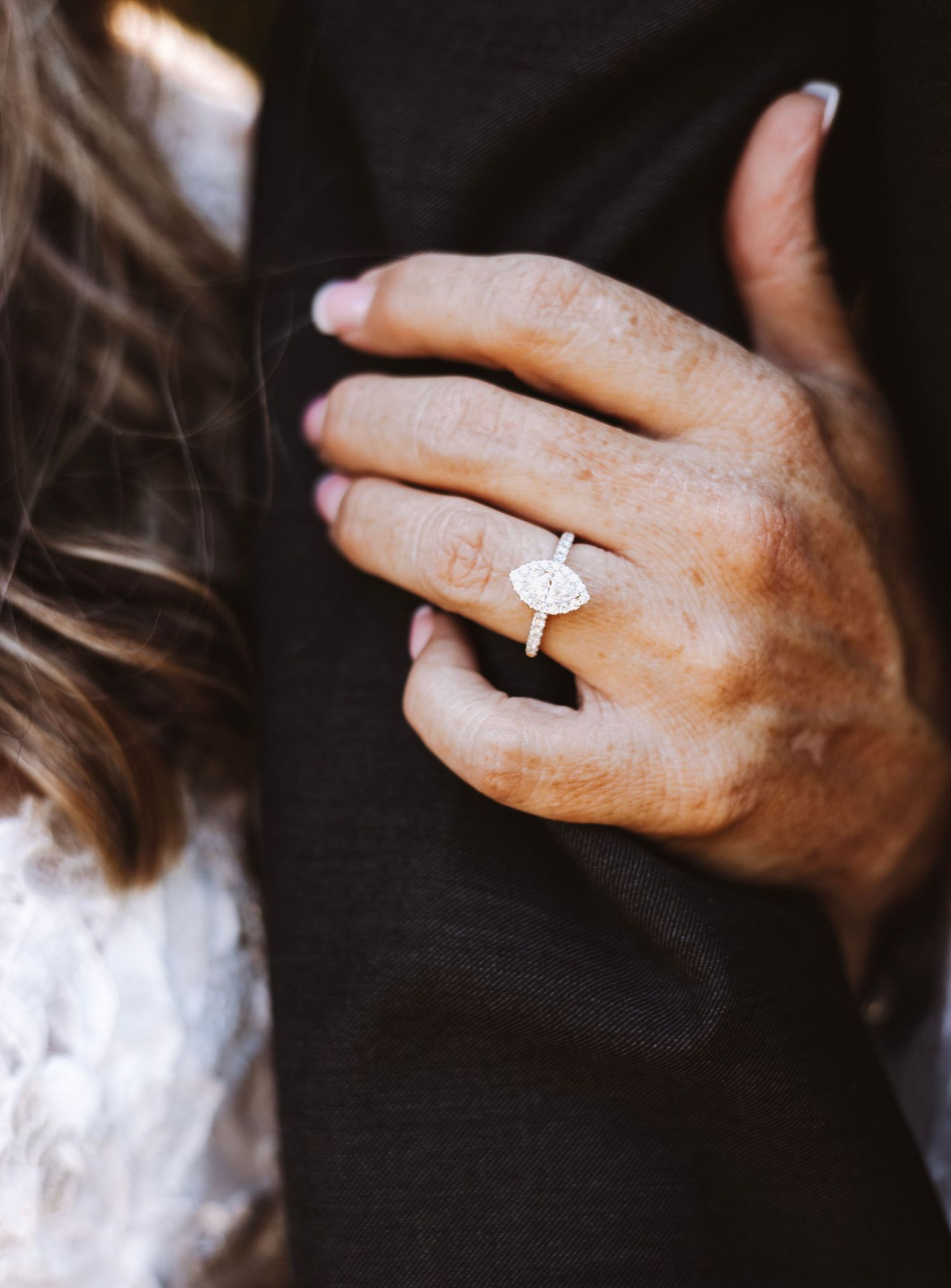 Close-up of a hand wearing an elegant oval diamond engagement ring.