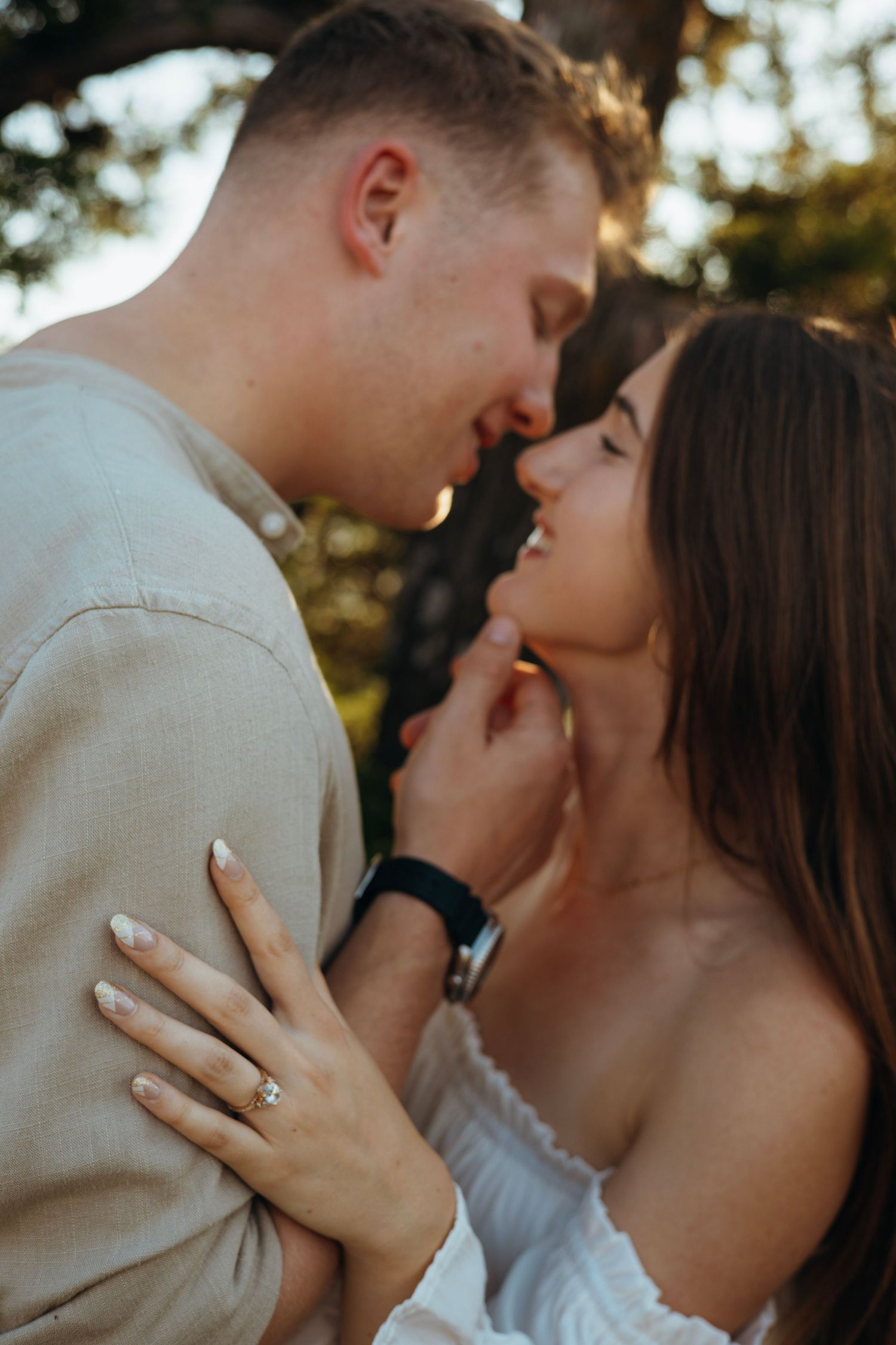 A passionate moment captured between a couple in white and beige against natural lighting.