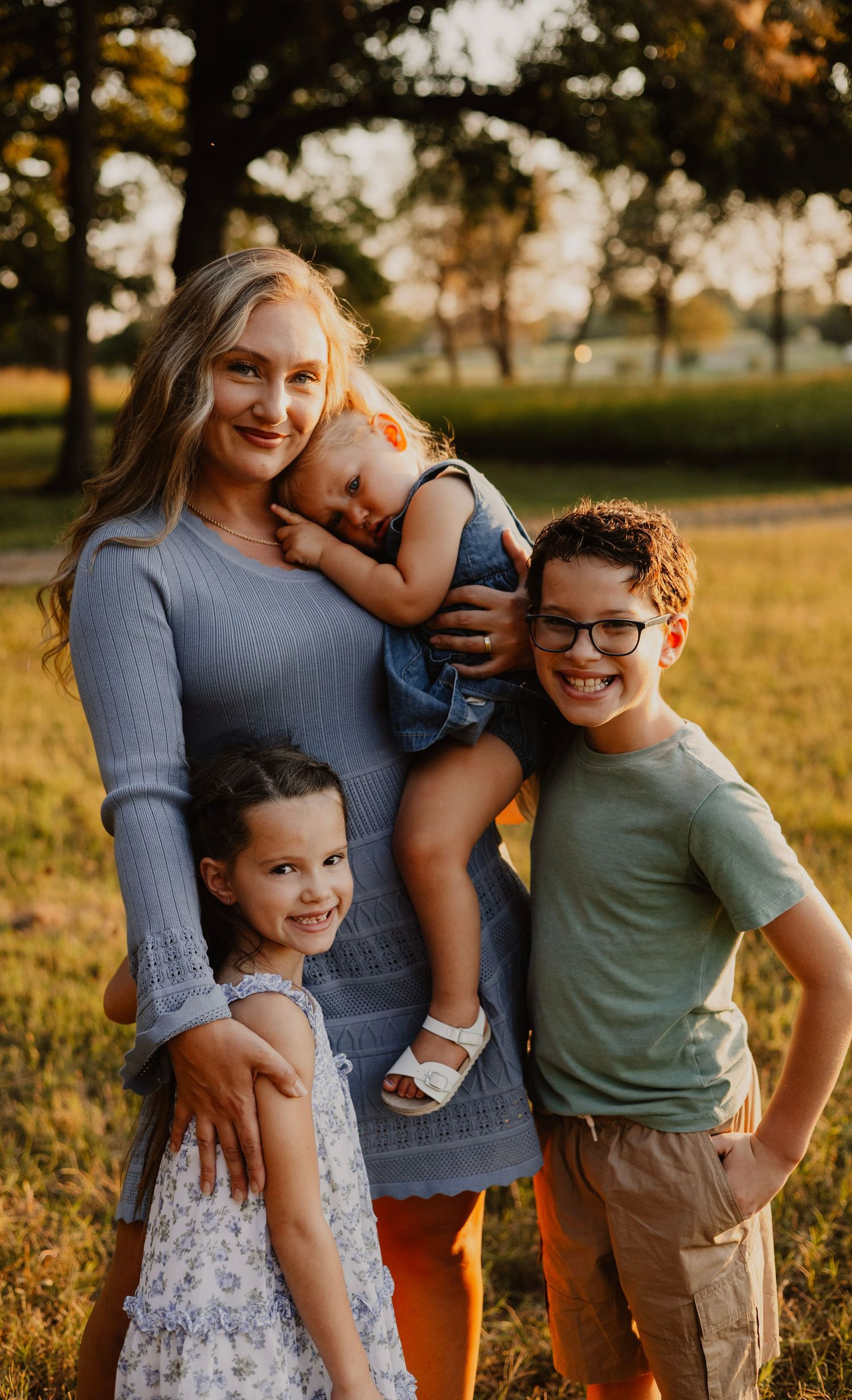 Mother and three children pose together in warm evening sunlight.