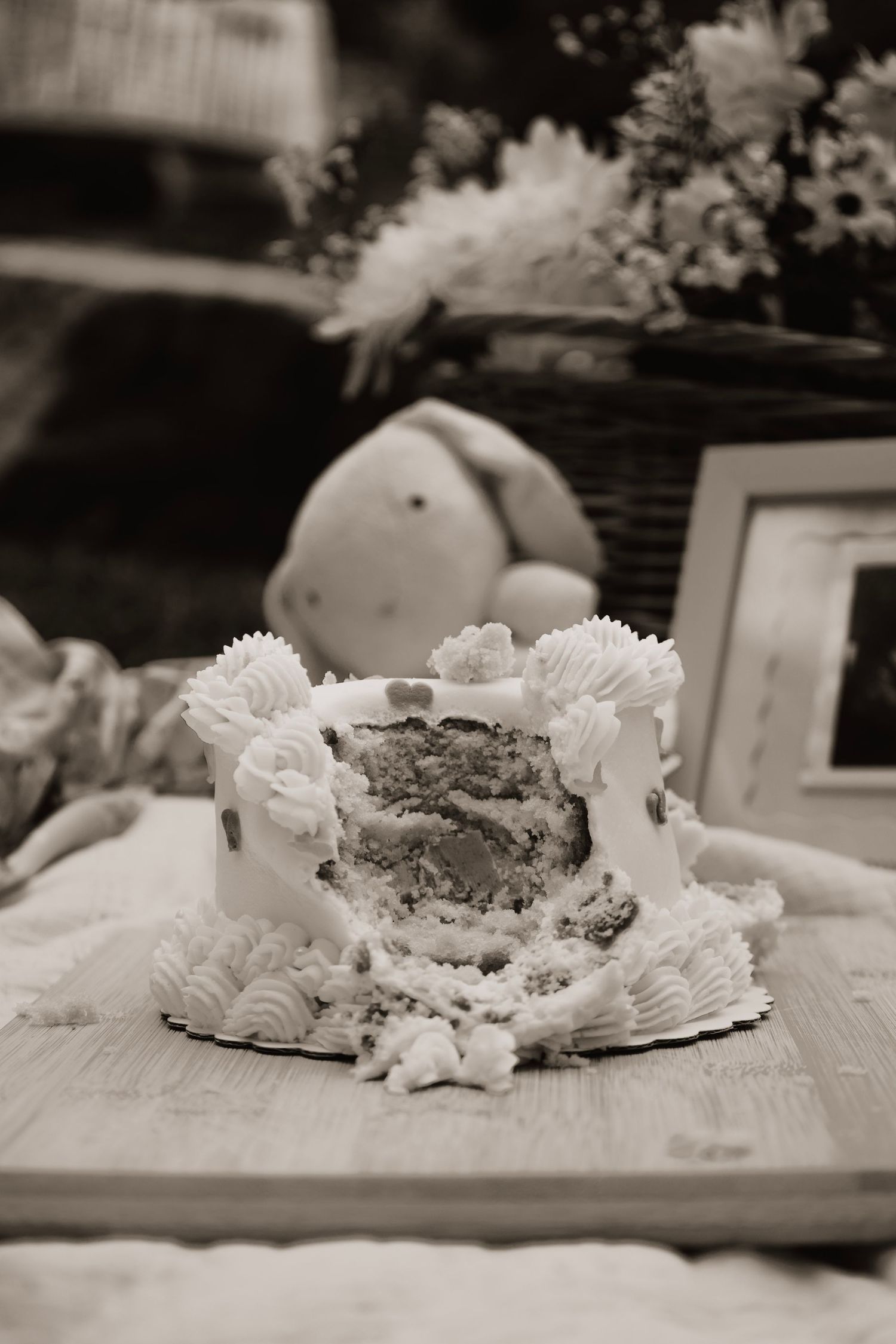 Black and white photo of a partially eaten cake with white frosting decorations.