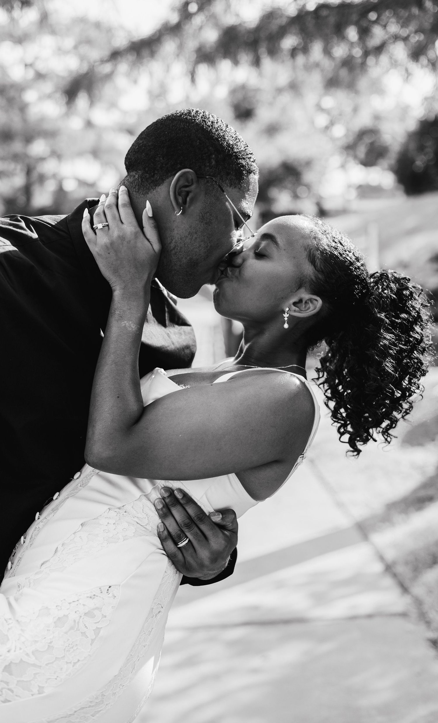 Black and white portrait of newlyweds sharing an intimate kiss outdoors.