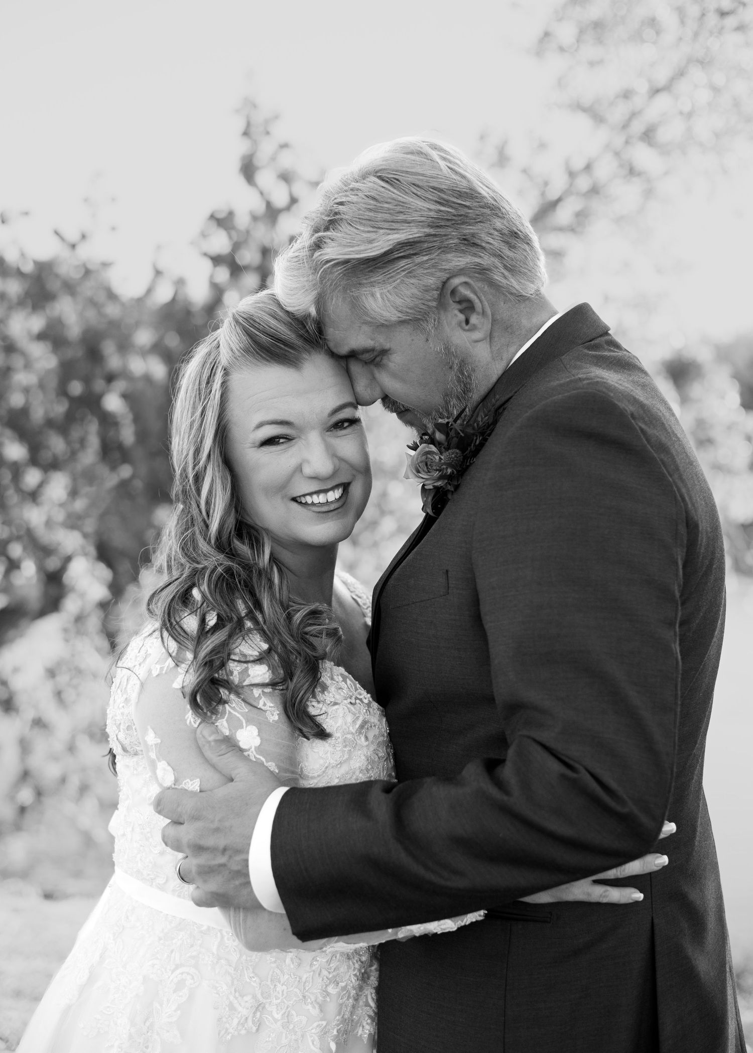 Black and white wedding portraits capturing tender moments between a couple outdoors.