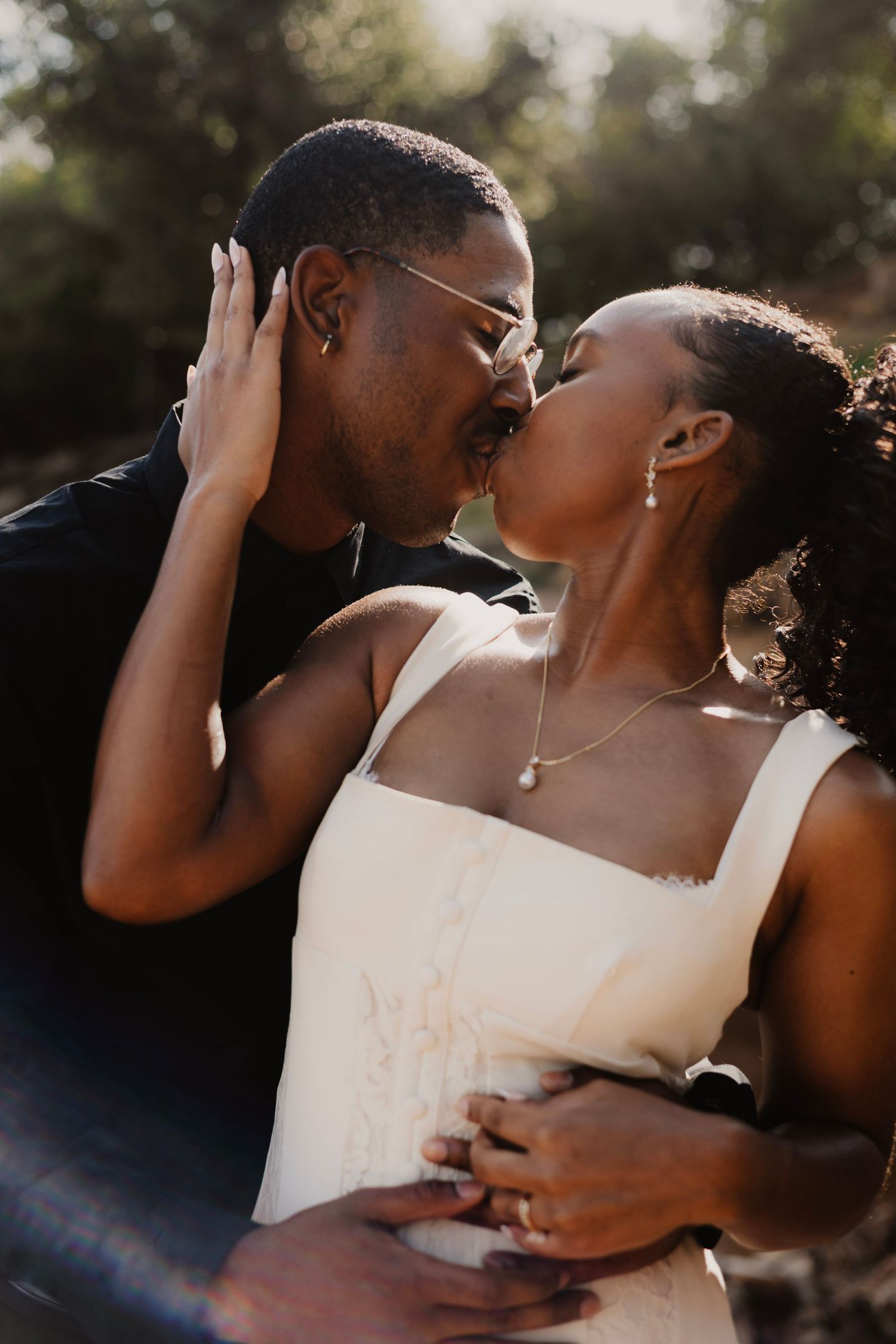 Intimate moment between newlyweds captured in warm sunlight outdoors.