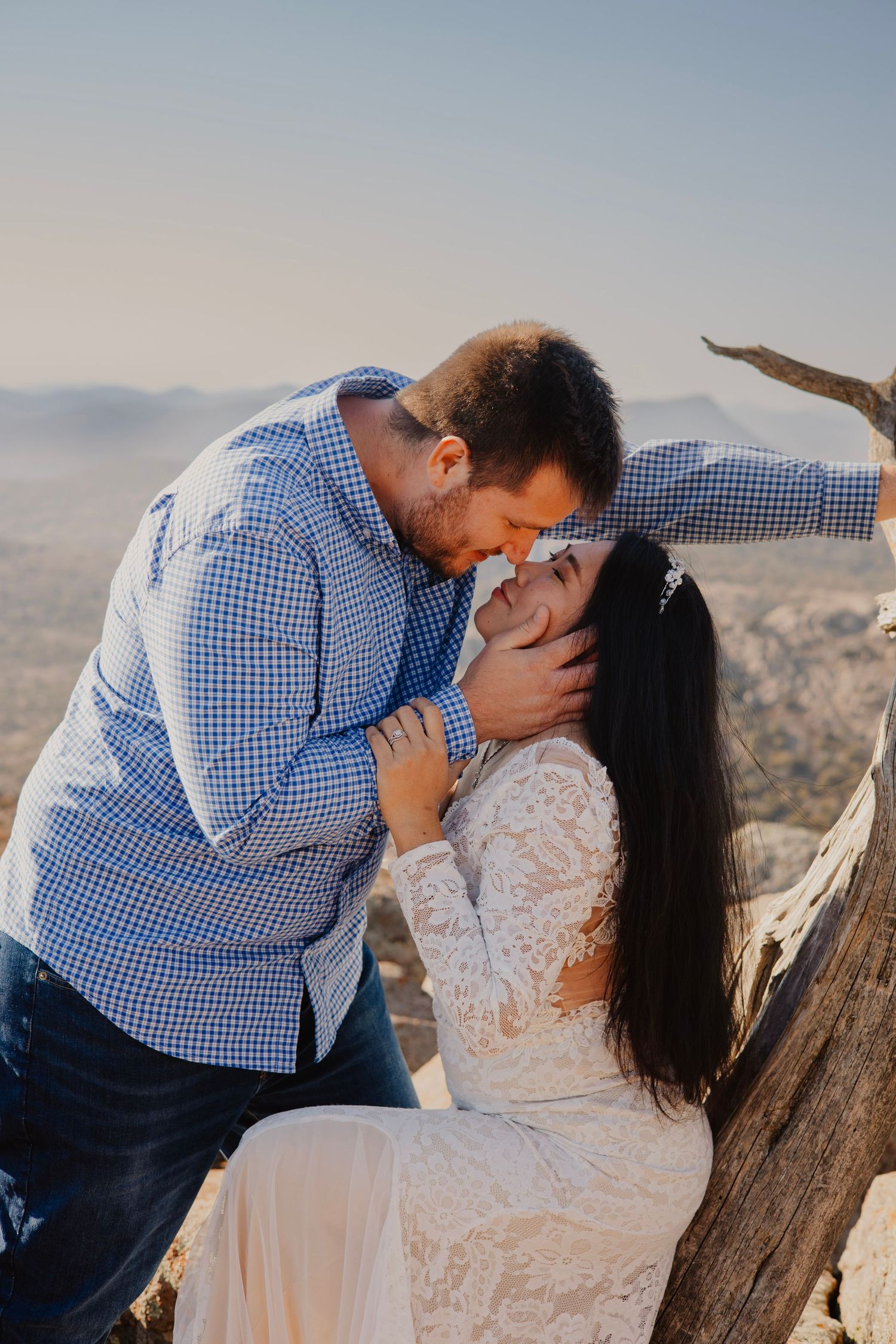 A romantic moment captured between a couple against a mountainous backdrop.