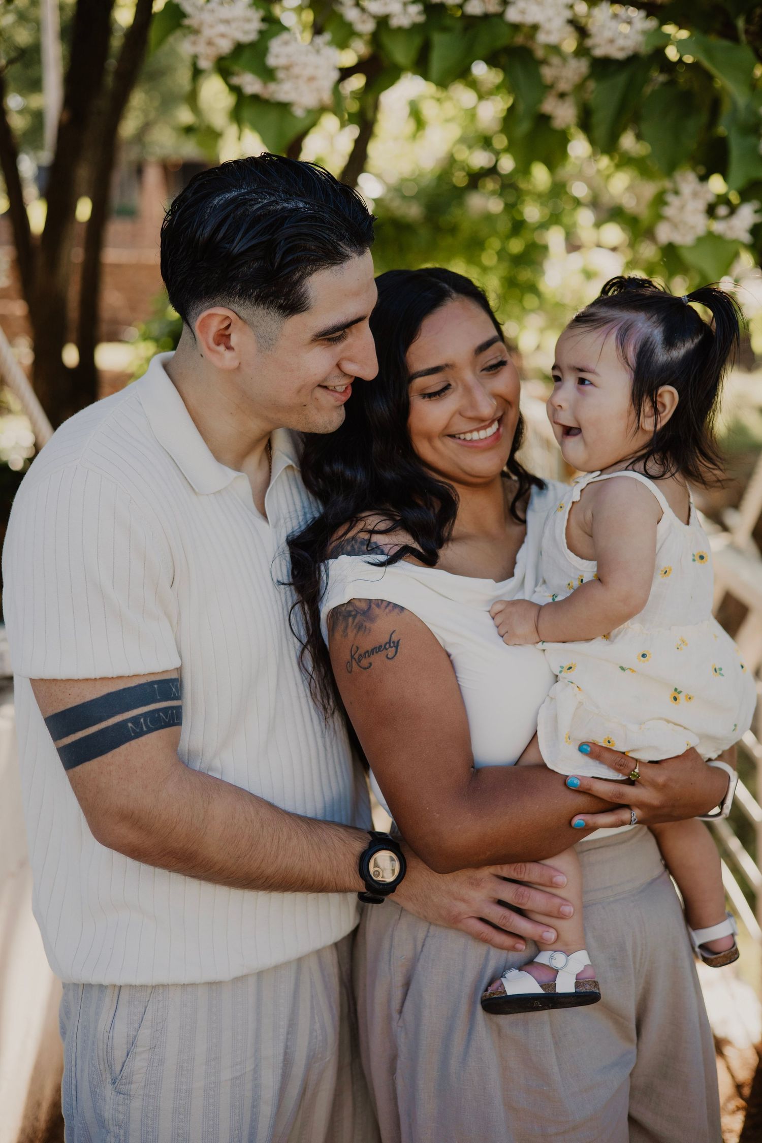 Family shares joyful moments together under blooming trees in outdoor setting.