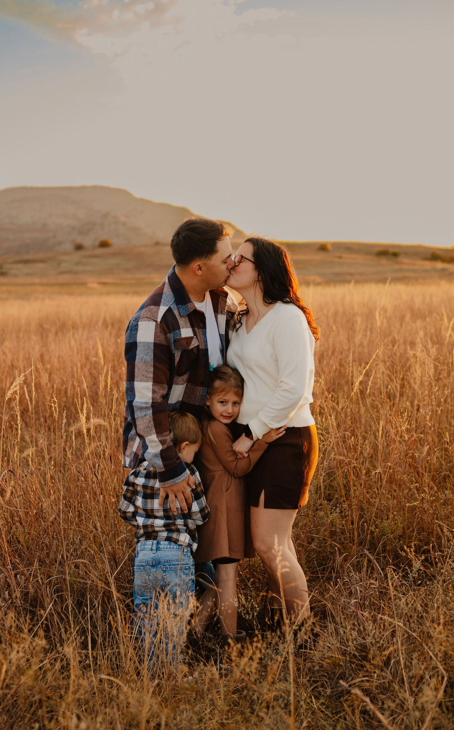 Intimate family moment captured in golden wheat field at sunset.