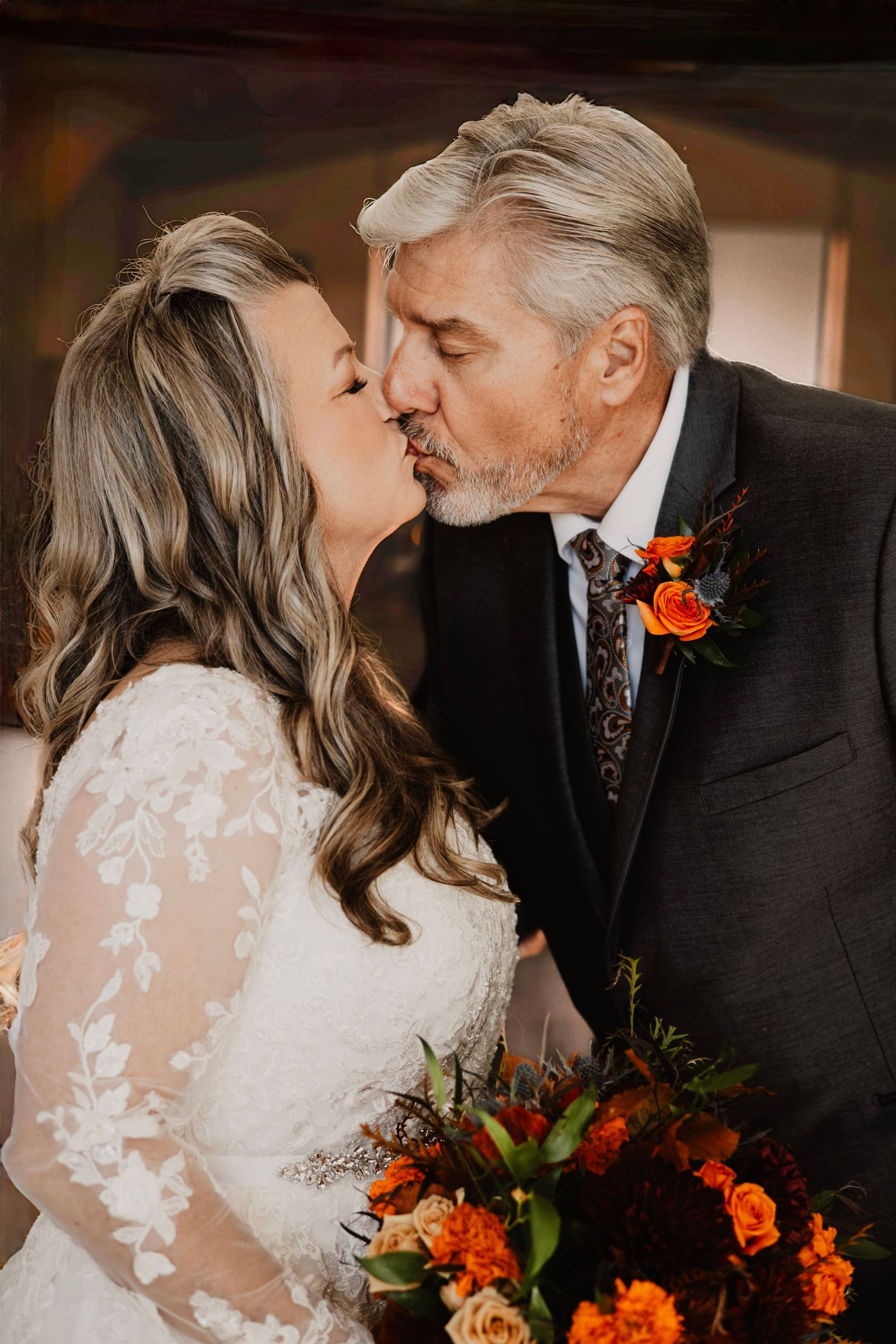 Wedding couple sharing intimate moments with orange floral bouquet accents.