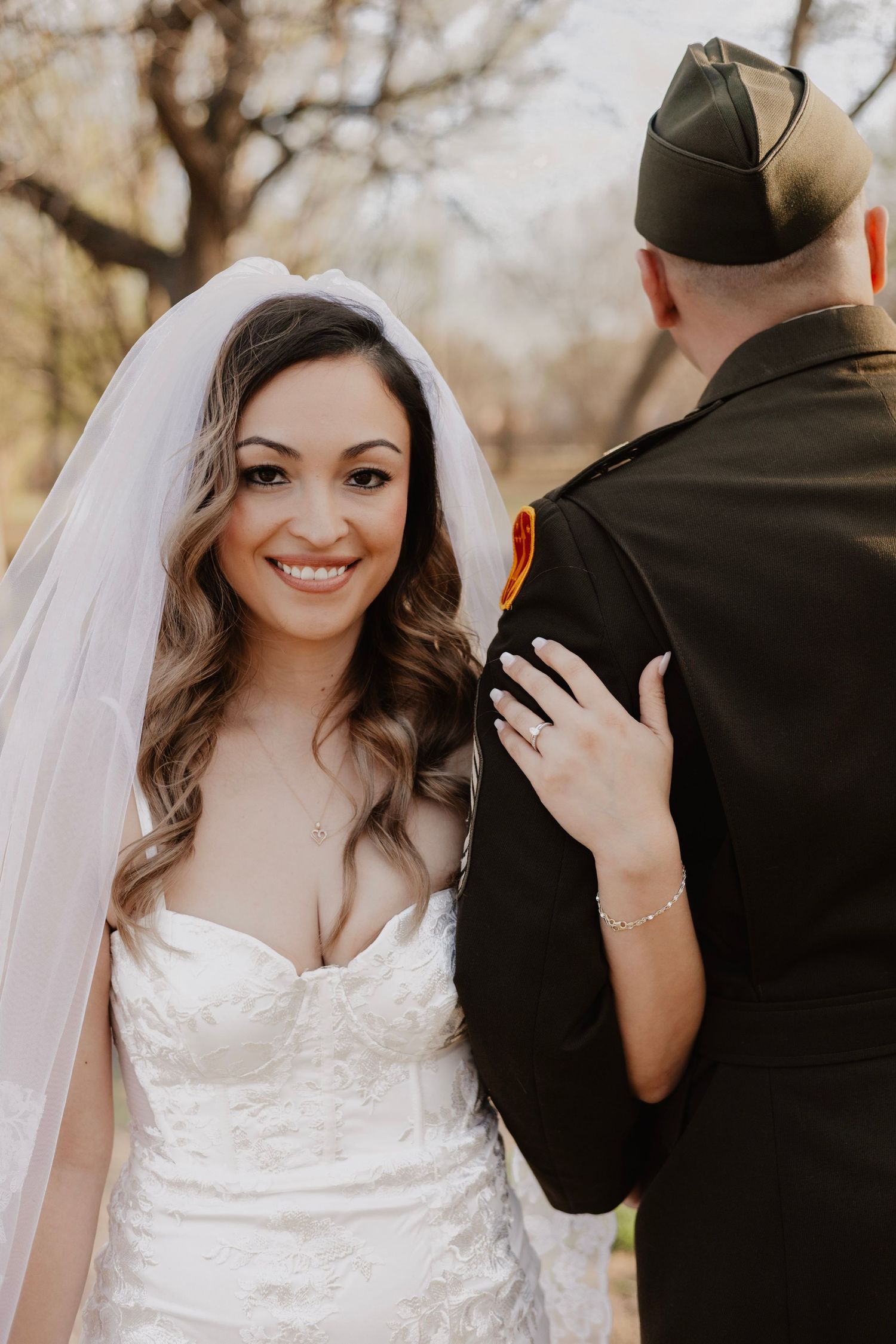 Bride in white lace dress shares joyful moments with military groom during first look.