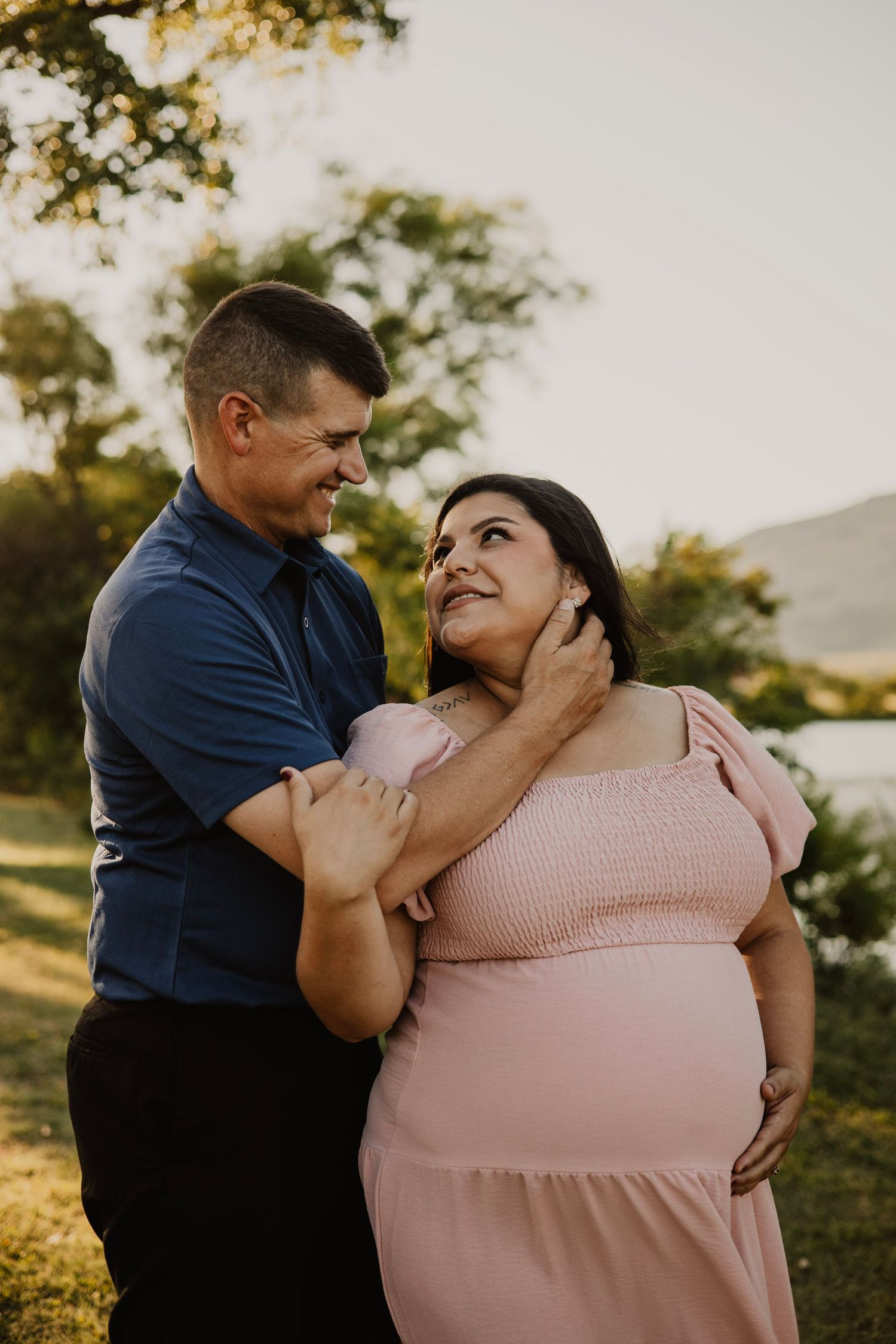 A romantic sunset portrait of a couple embracing outdoors in golden light.