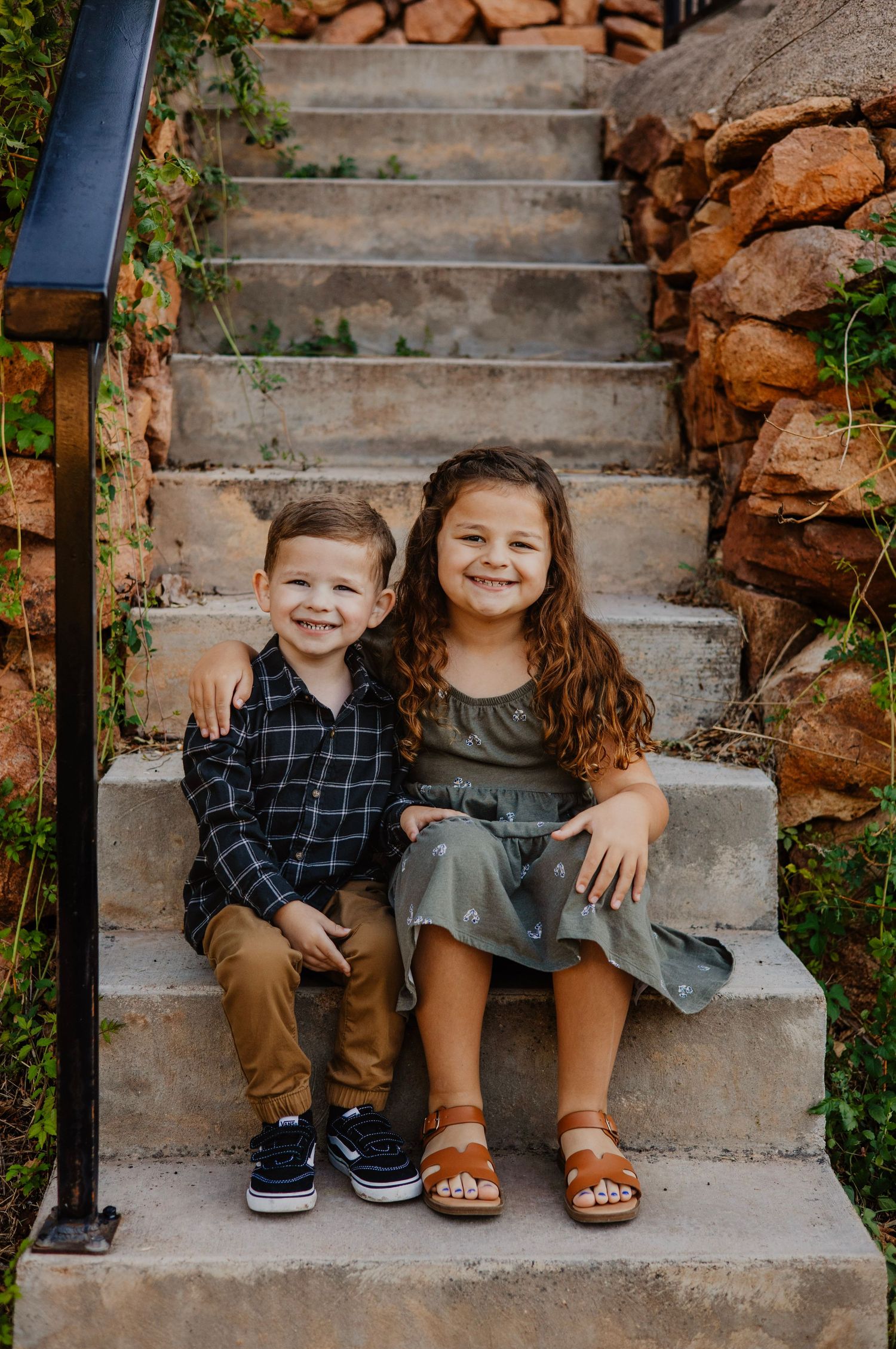 Two children sit together on stone steps sharing a sweet moment outdoors.