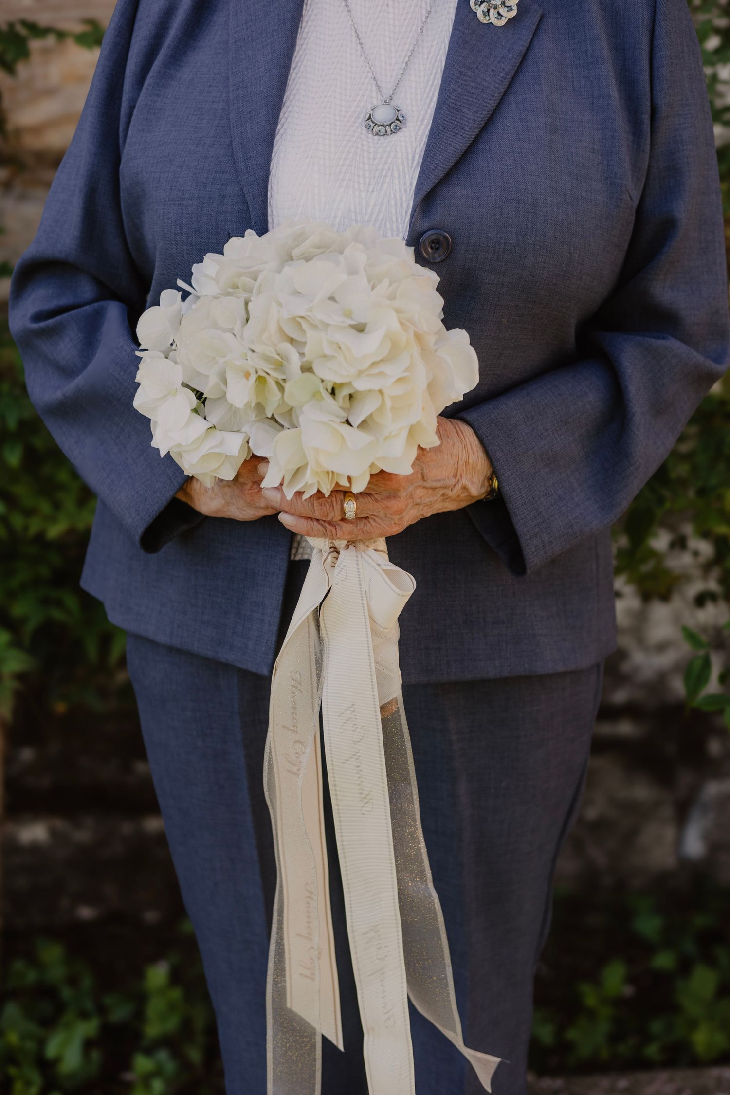 Close-up of white hydrangea bouquet held against navy blue suit.
