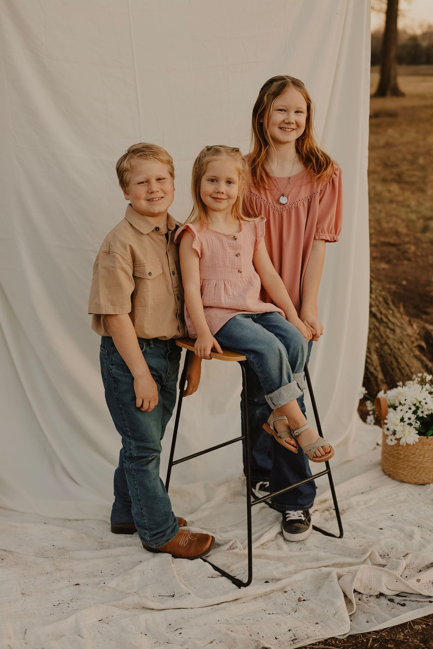 Family portrait session with rustic elements and casual attire against white backdrop.