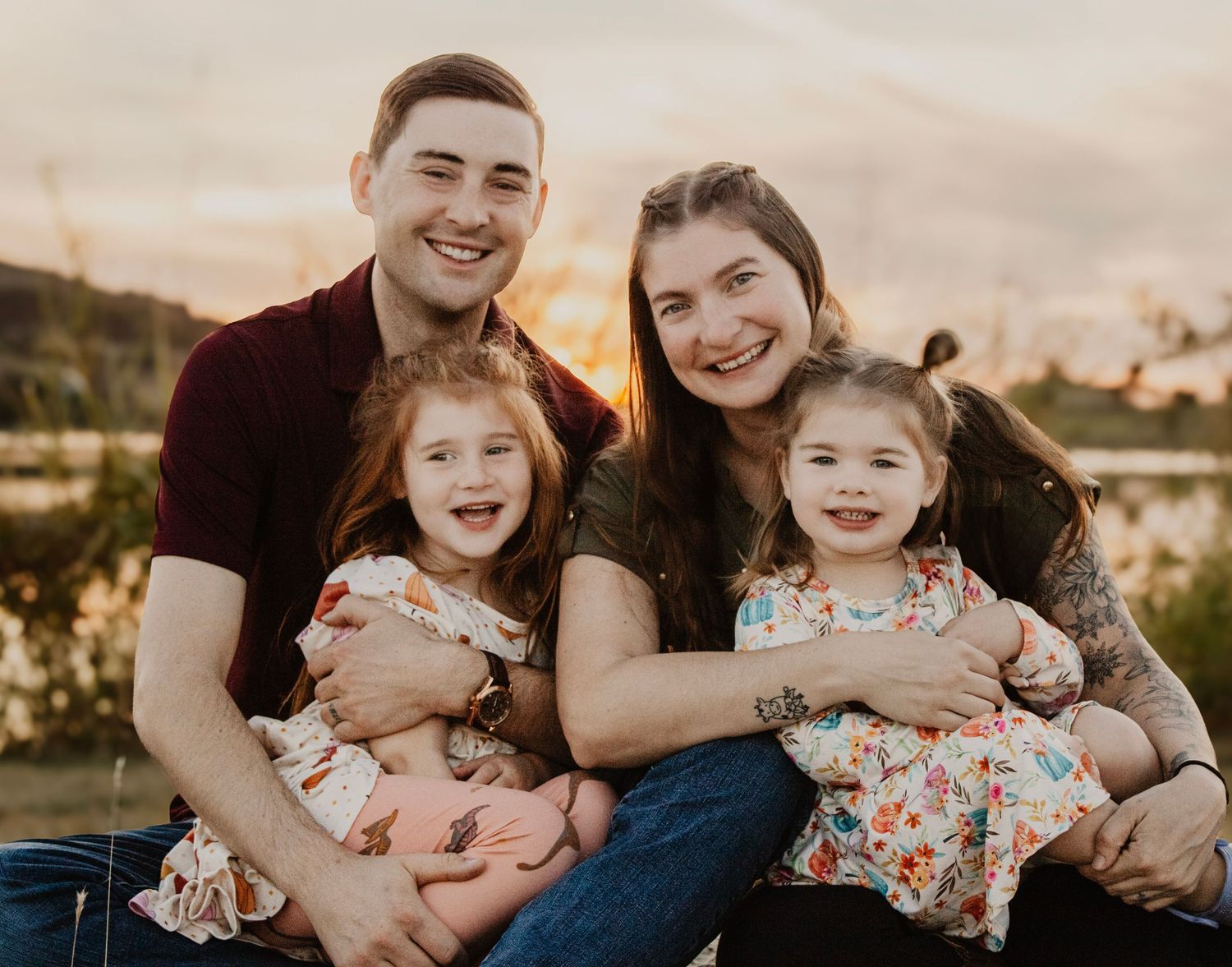 Loving family cuddles together during sunset outdoor photo session.