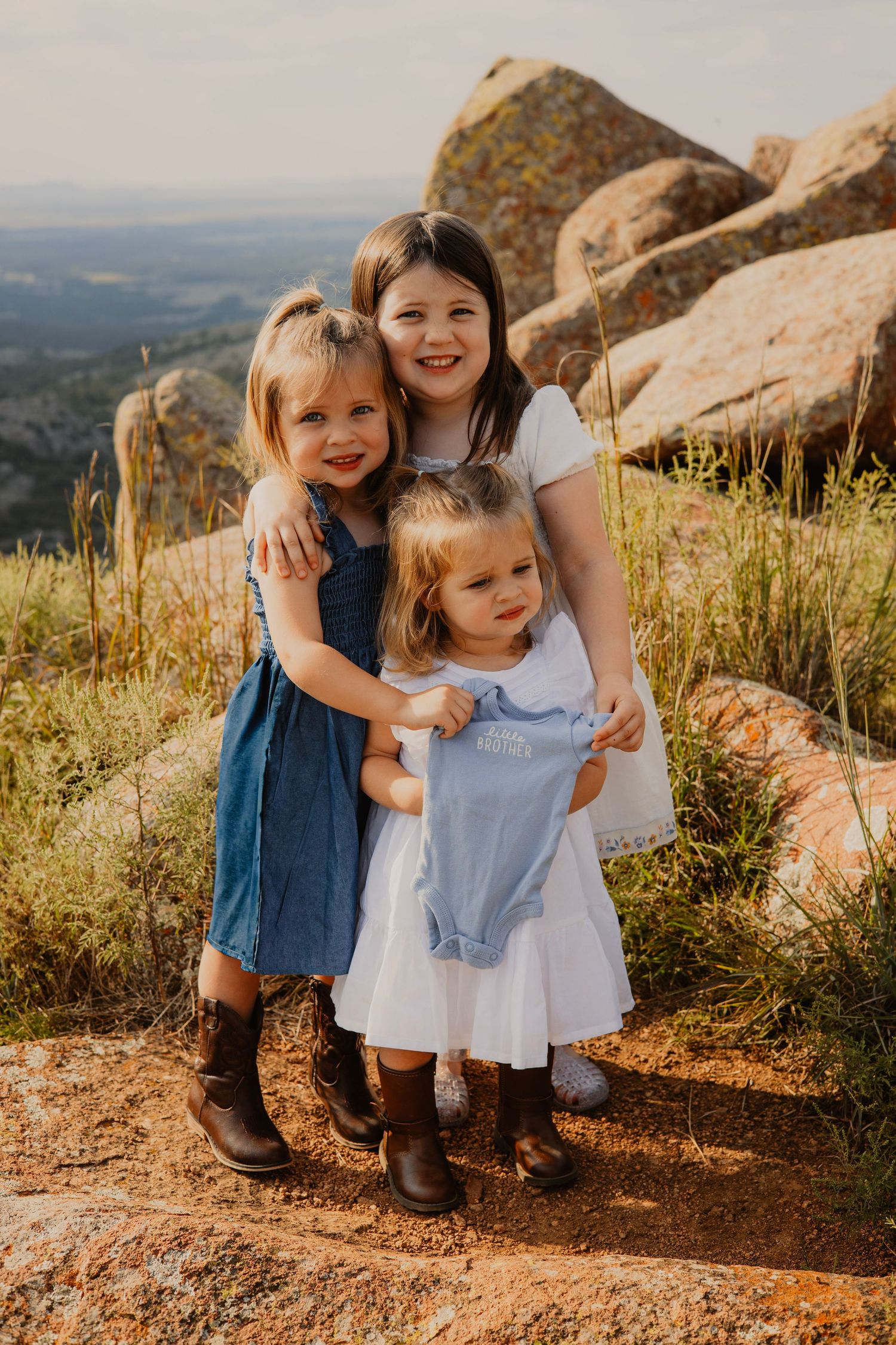 Children sitting together on rocky mountain terrain during golden hour.