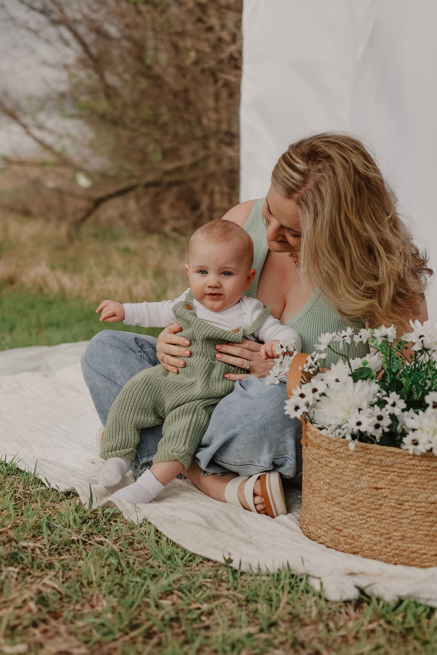Sweet candid moments between parent and child on picnic blanket with spring flowers.