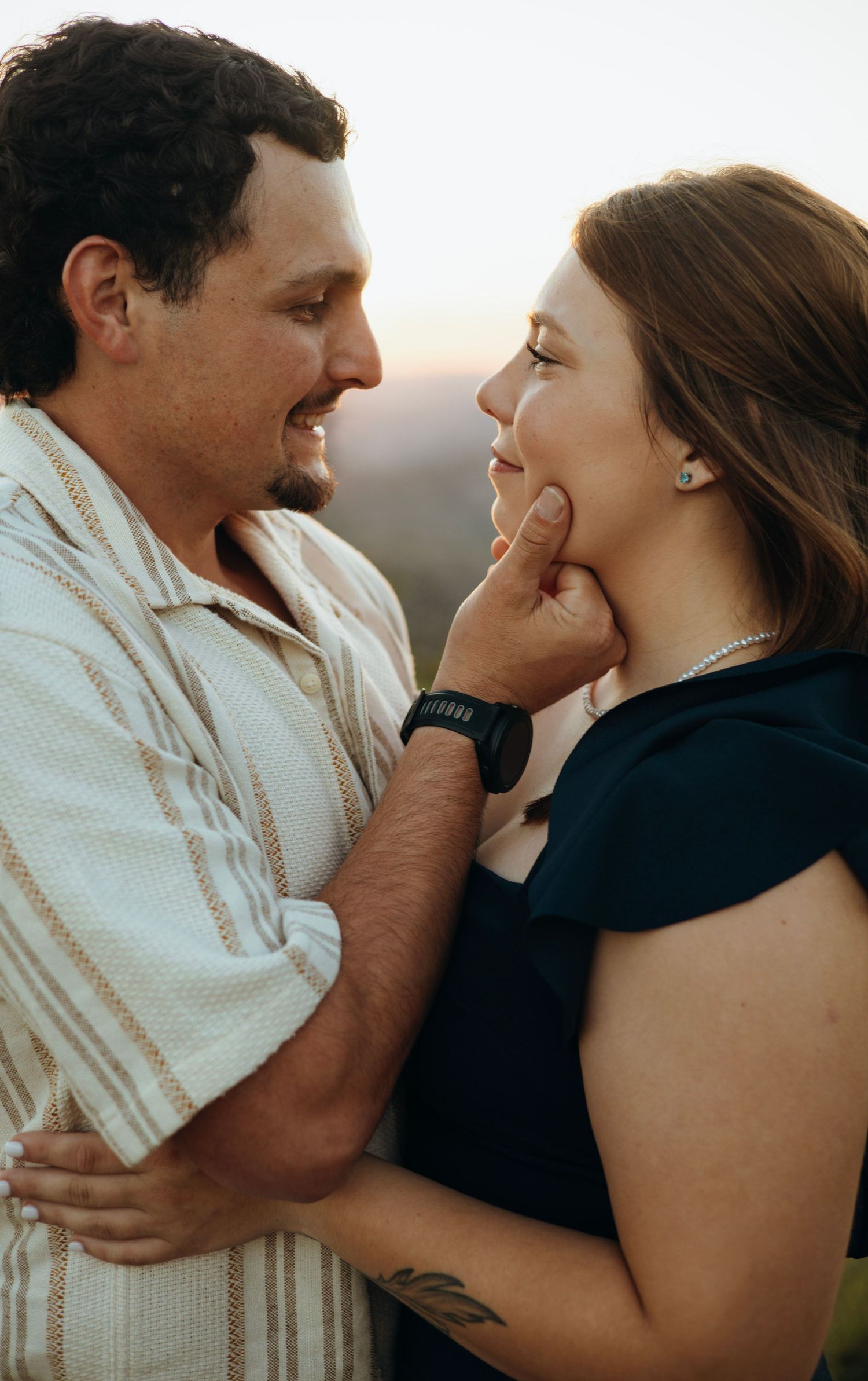 A close-up romantic portrait of a couple sharing an intimate moment at sunset.