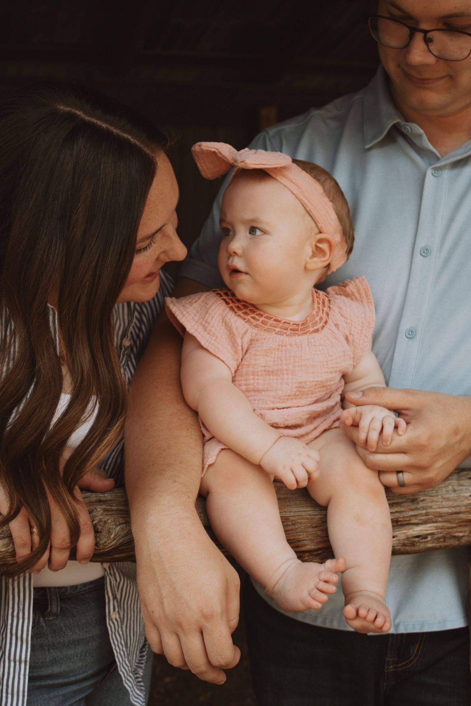 Family shares intimate moment together while sitting on rustic wooden bench.