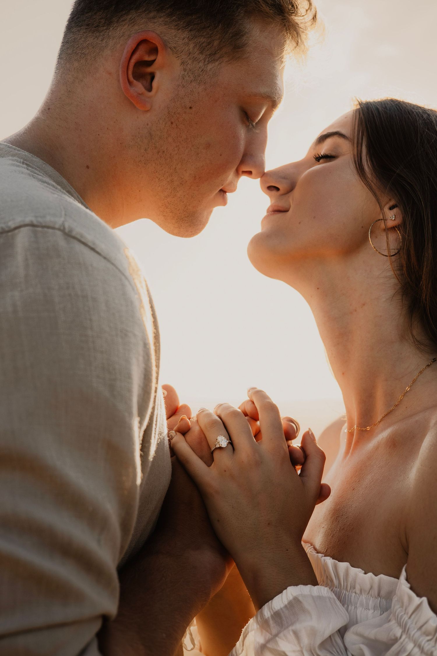 A romantic couple sharing an intimate moment at sunset with their hands clasped together.