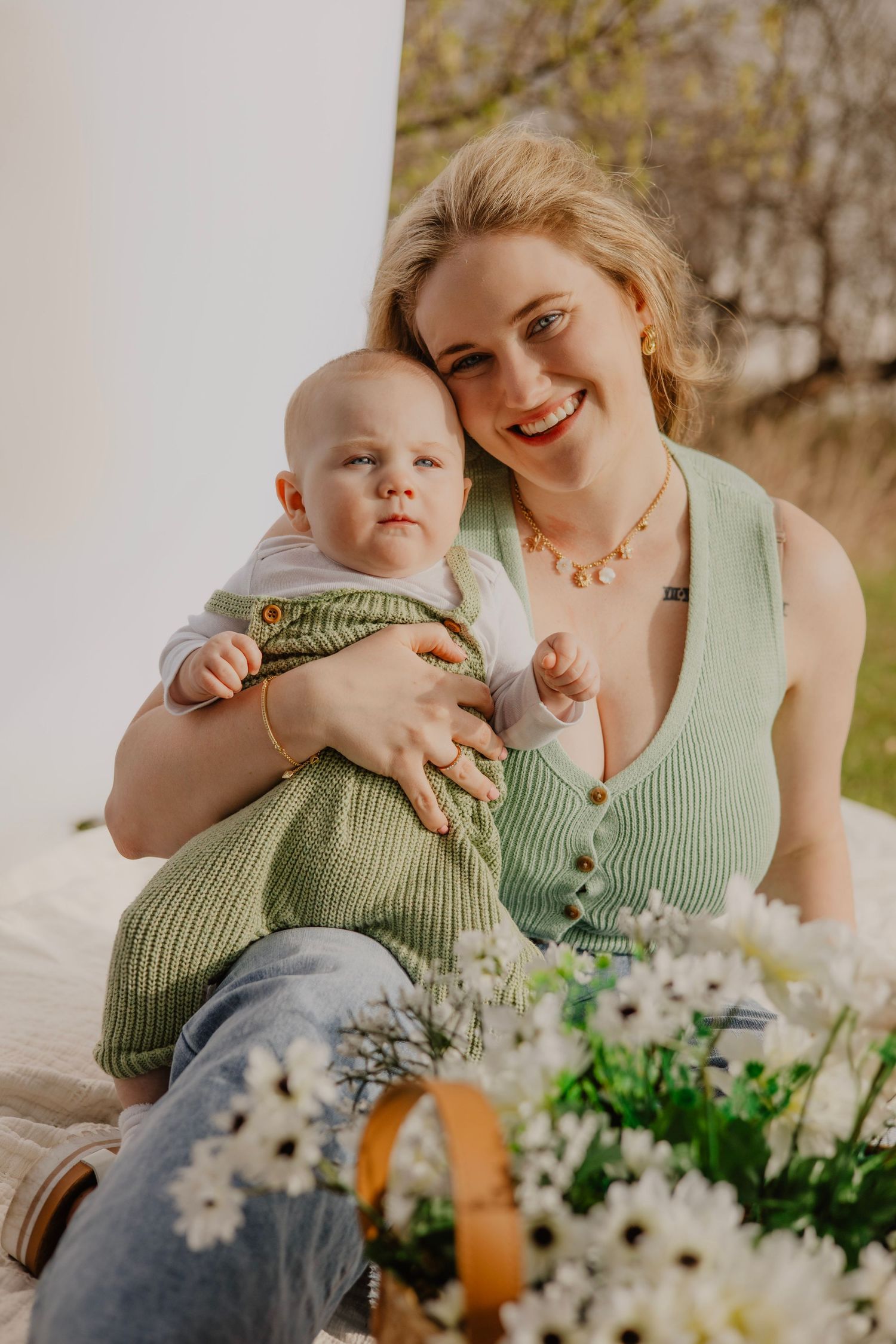 Playful moments captured between parent and baby with spring flowers on white backdrop.
