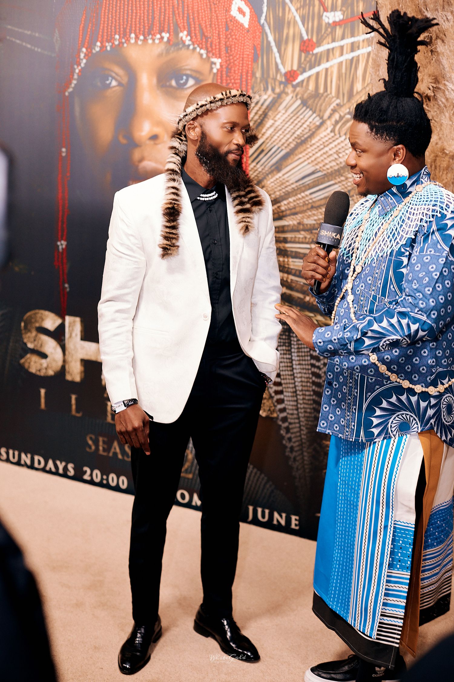 Two men in traditional African attire at Shaka Ilembe TV show premiere.