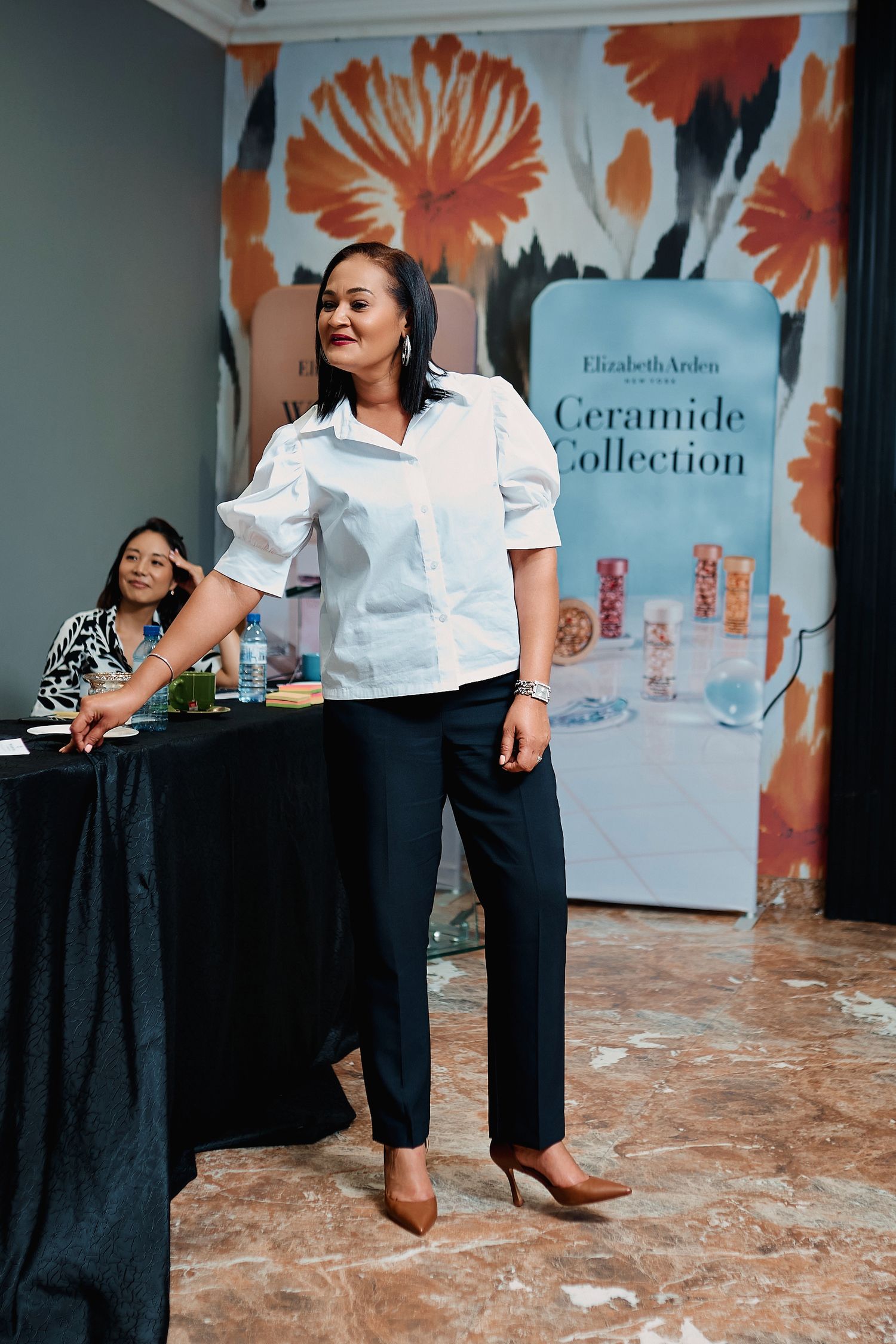 Woman in white blouse and black pants presents at Elizabeth Arden Ceramide Collection event.