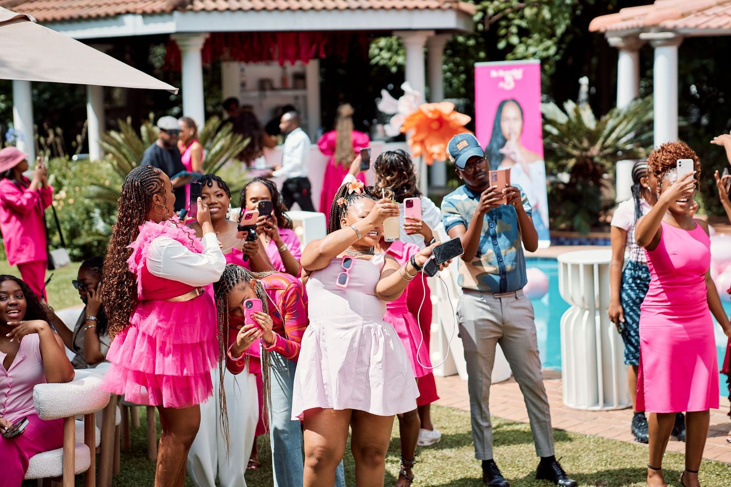 Guests in pink outfits celebrate outdoors at a vibrant pink-themed party event.