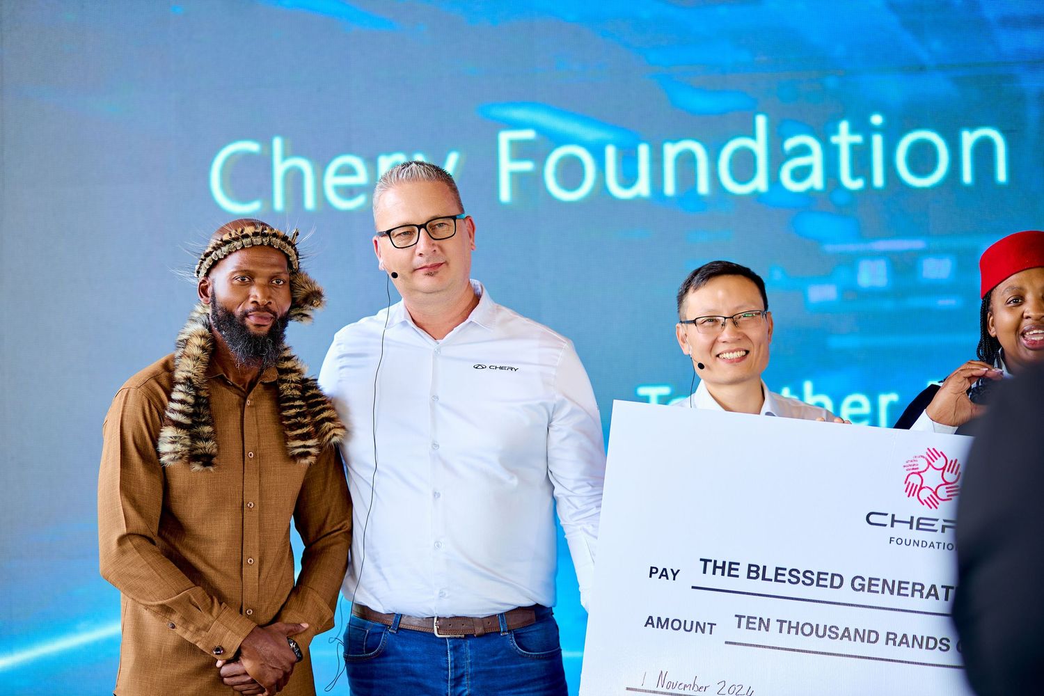 Four people posing with oversized Chery Foundation charity check for ten thousand rand.