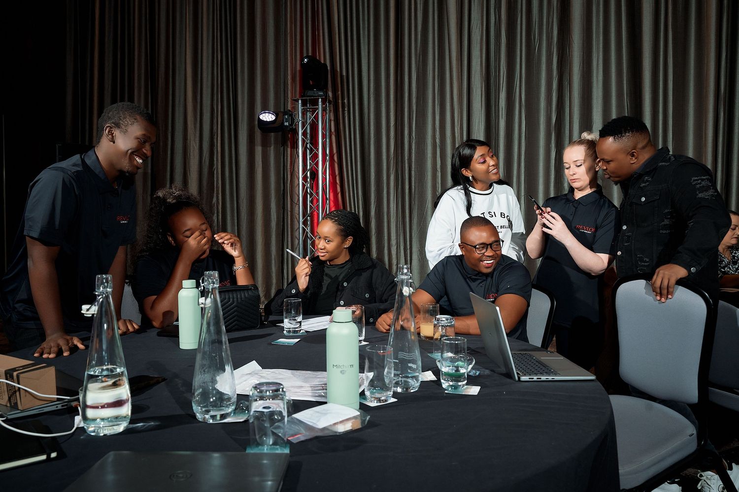 Group of diverse event professionals reviewing content on devices at a dark conference room table.