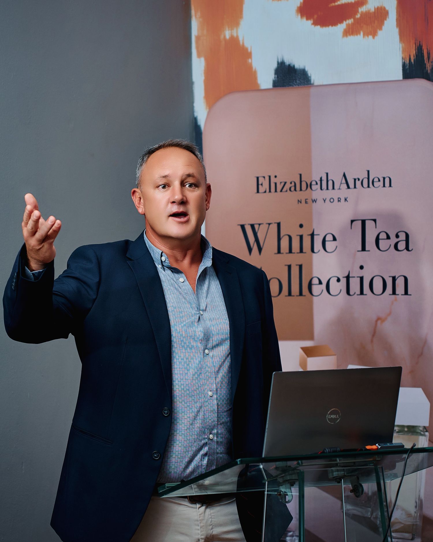 Man presenting Elizabeth Arden White Tea Collection at a product launch event.