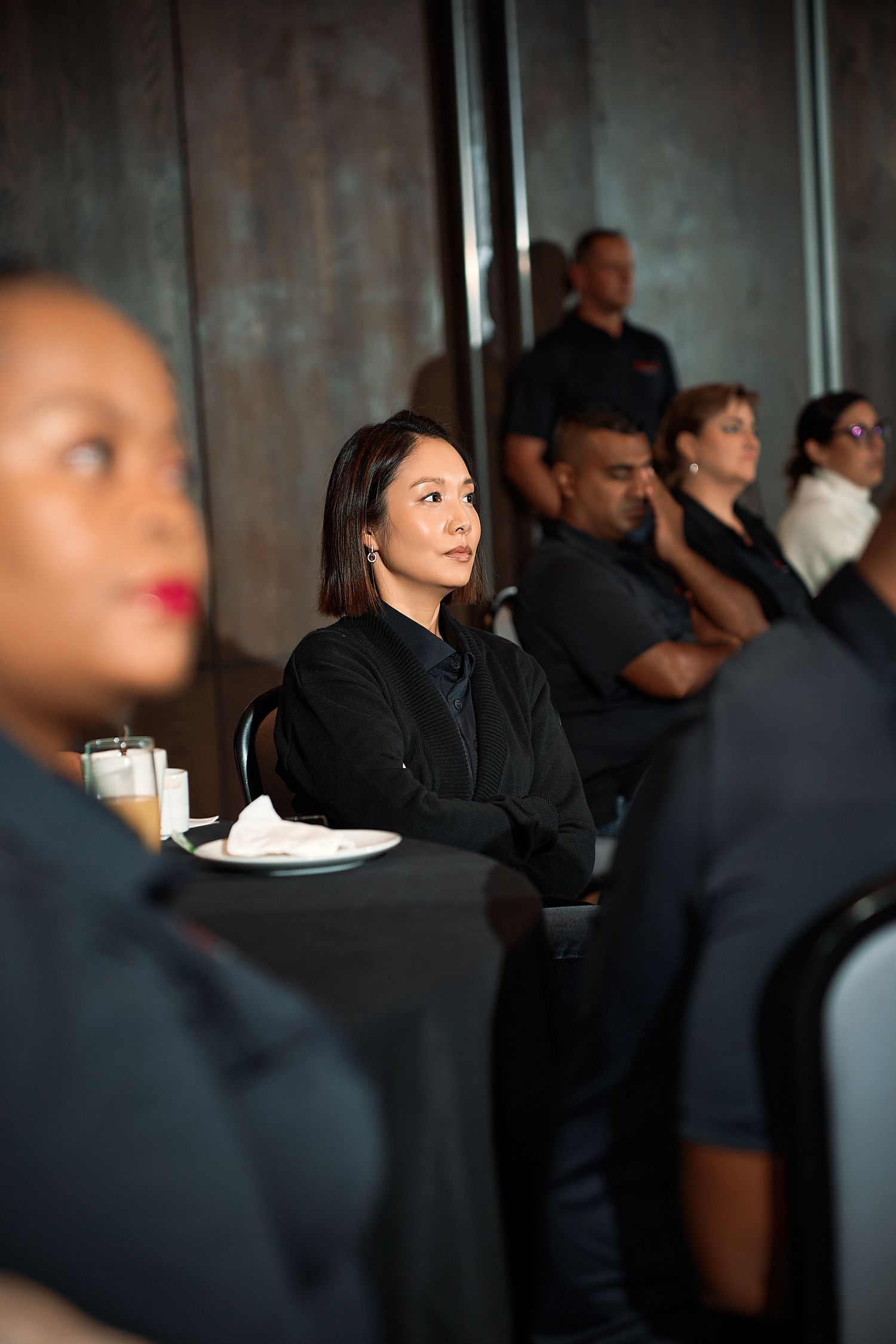 Diverse group of professionals seated at tables during a corporate conference or business event.