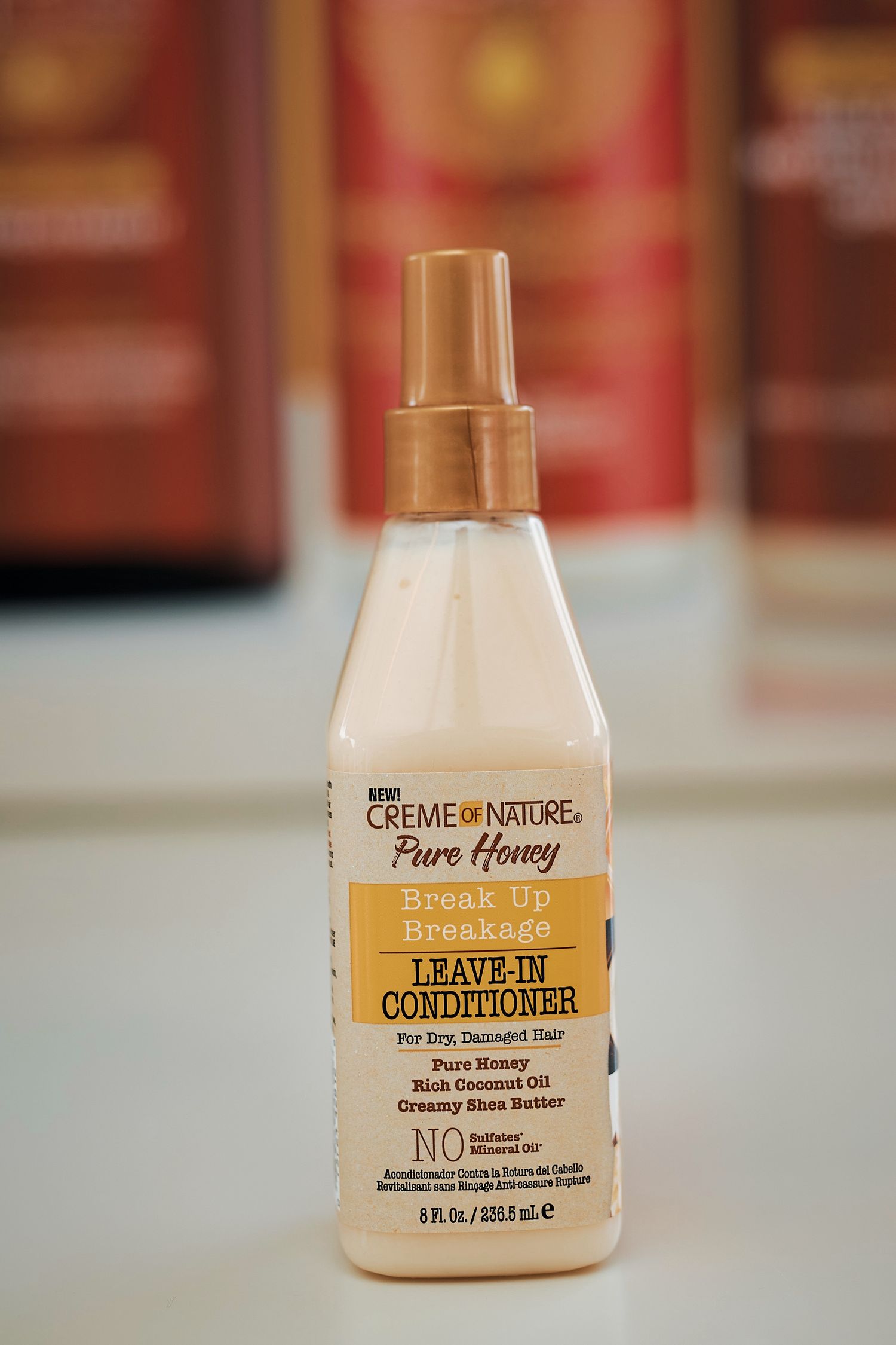 Creme of Nature Pure Honey Break Up Breakage Leave-In Conditioner spray bottle on shelf.