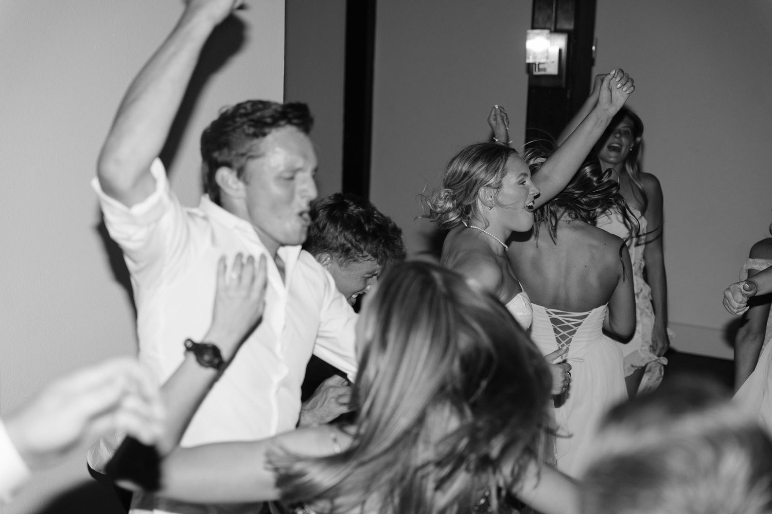 Wedding guests dancing energetically at a lively black and white wedding reception.