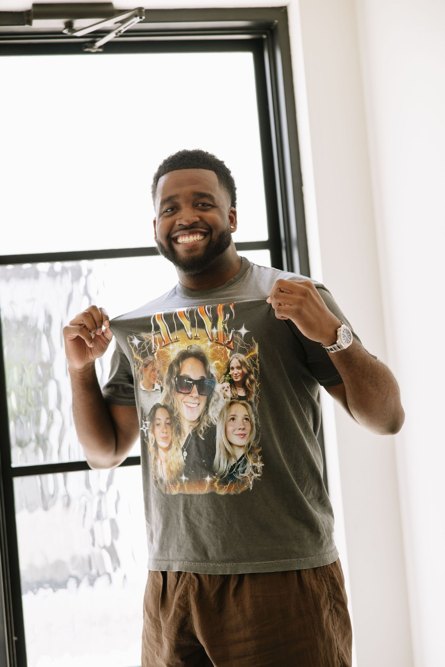 Smiling groom proudly displaying a custom graphic t-shirt featuring photos of the bride as a wedding day gift.