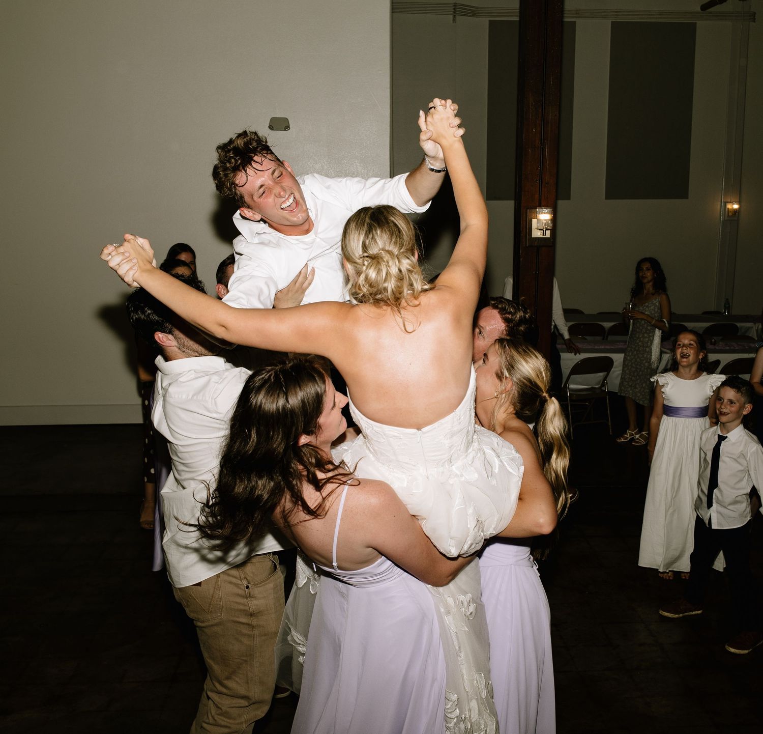 Bride and groom lifted by friends during a fun and celebratory wedding reception dance.