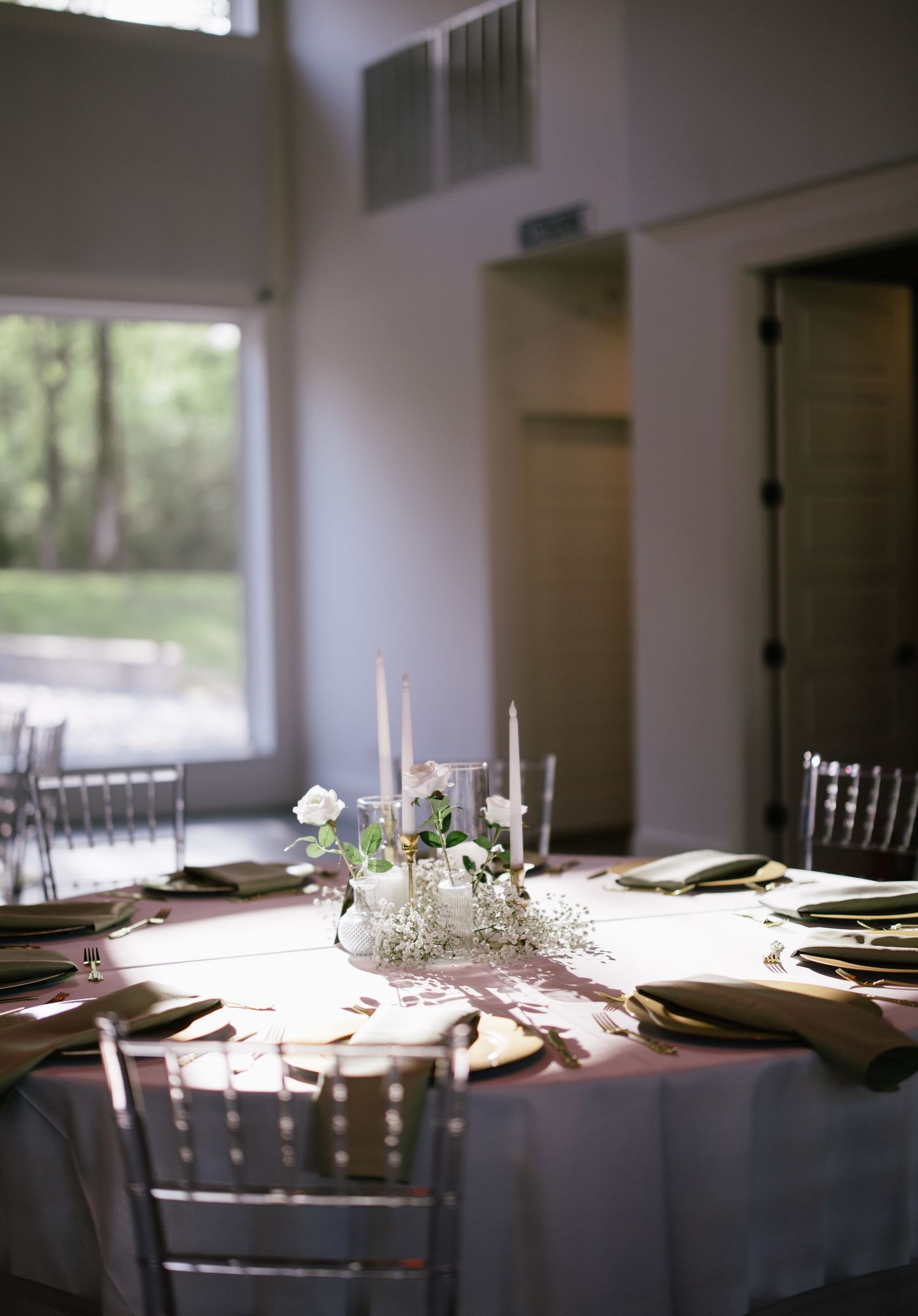 Wedding reception table with white roses, candles, and gold charger plates.