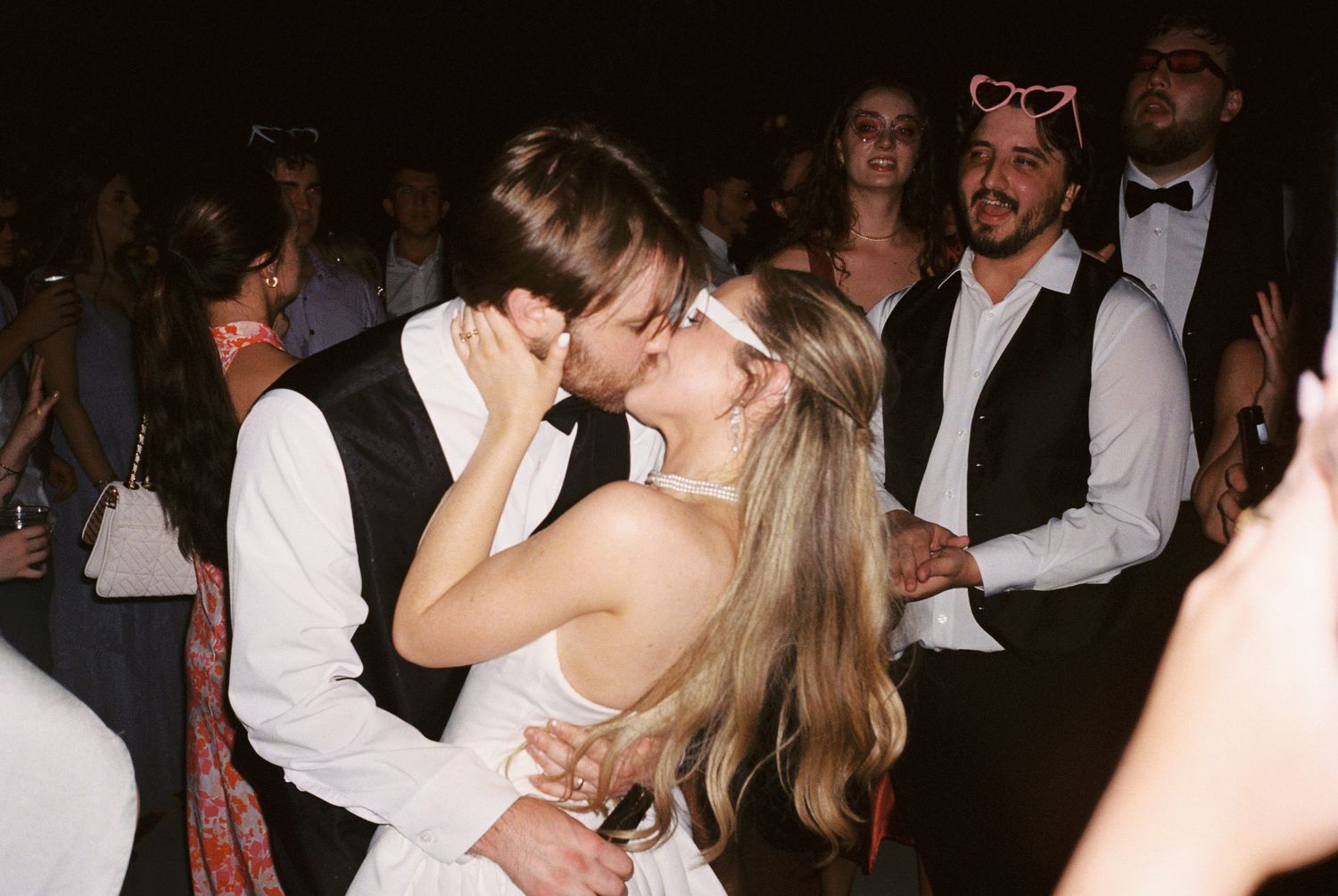 Bride and groom share a passionate kiss on the dance floor at their wedding reception.