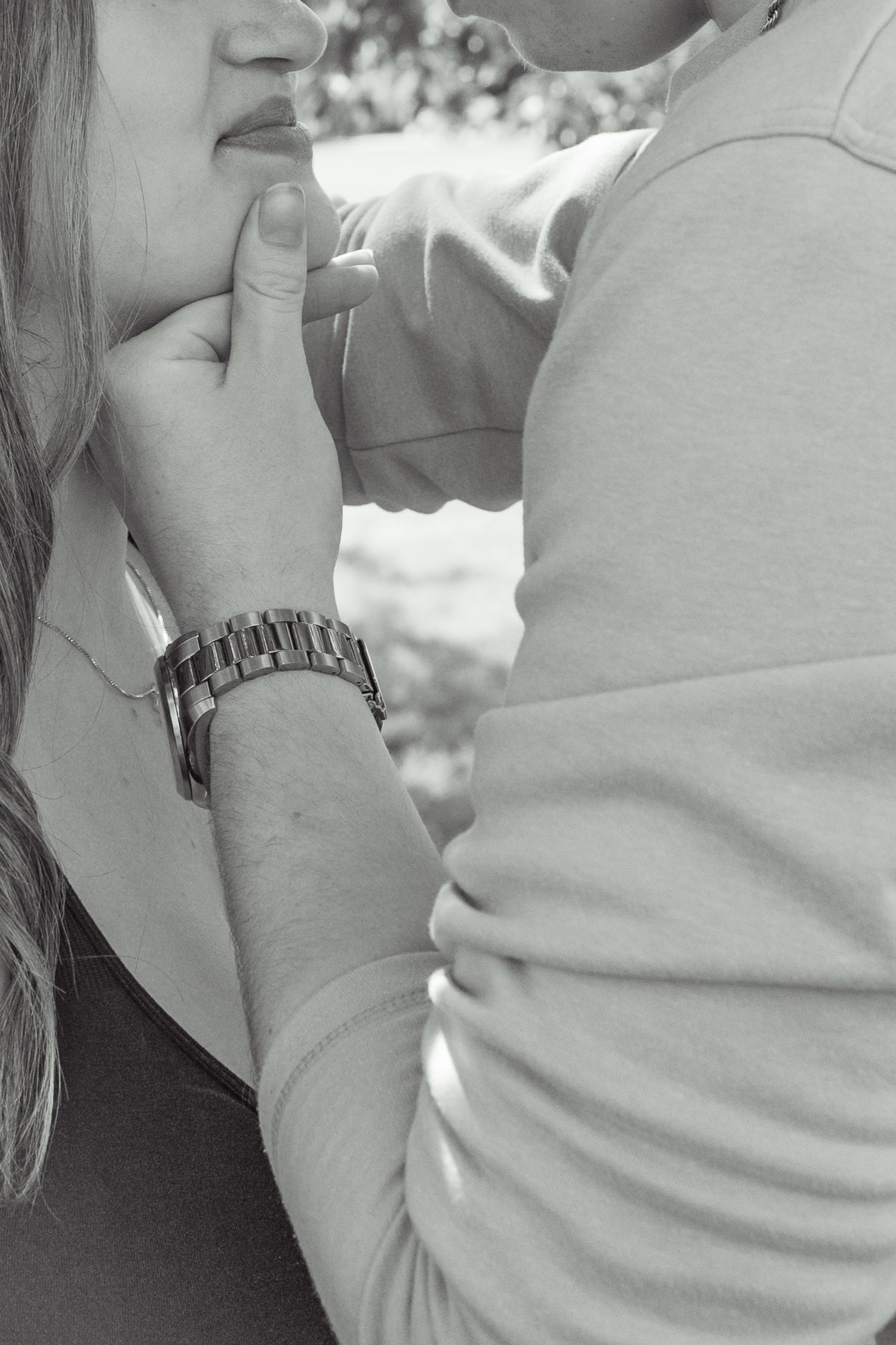 Black and white photo of a couple sharing an intimate moment, man gently holding womans face while kissing.