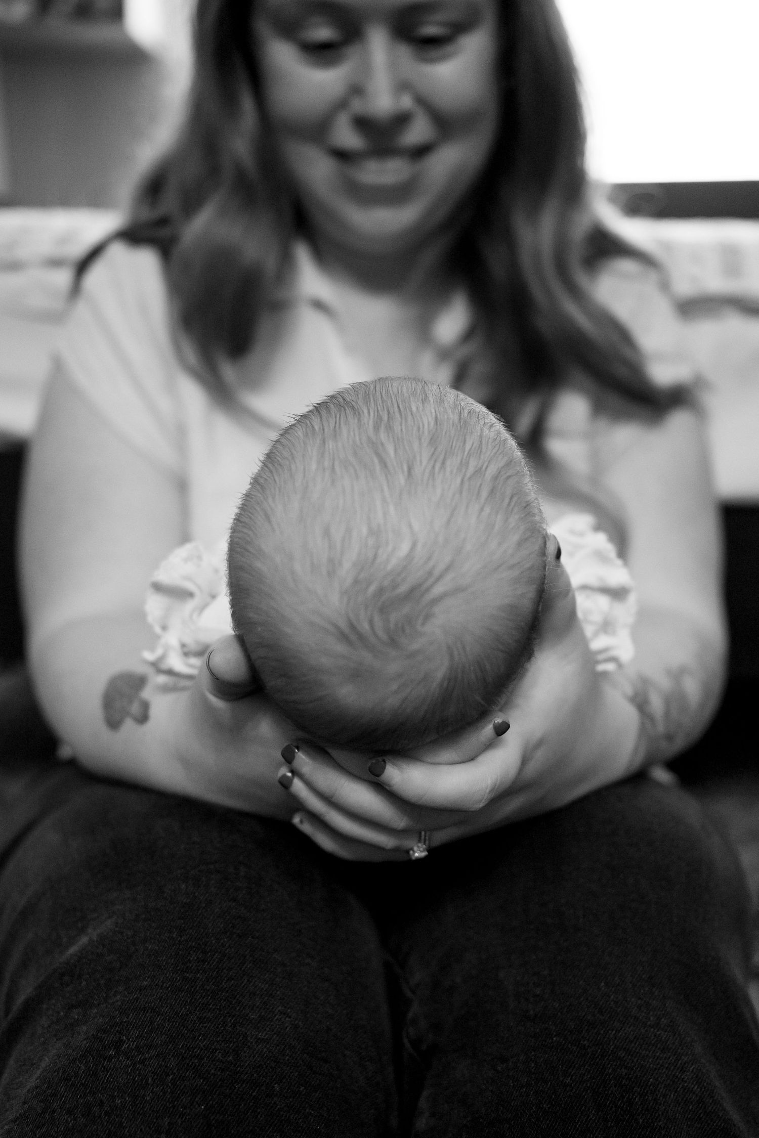 Black and white photo of a smiling mother tenderly holding her newborn baby in her arms.