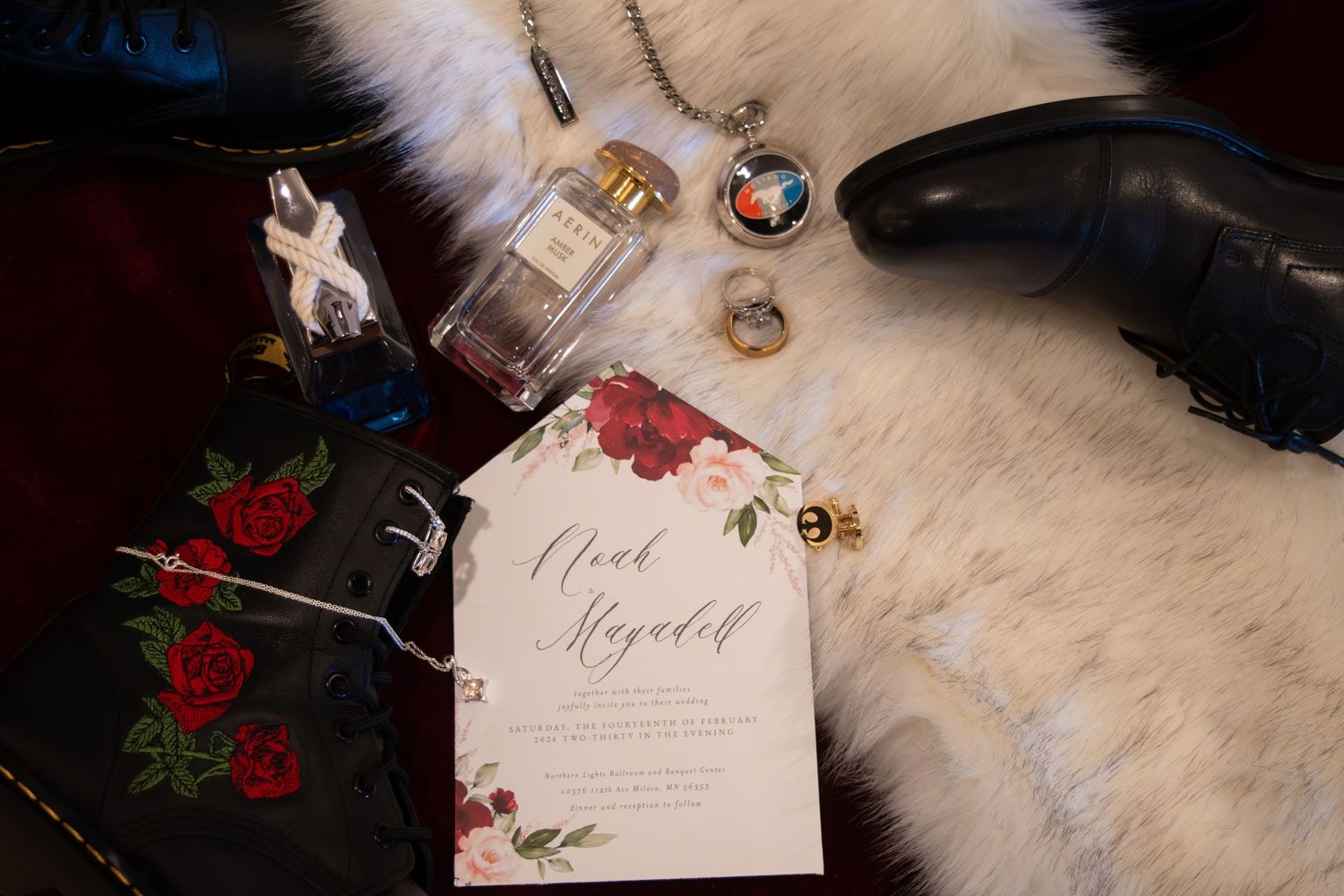 Elegant wedding flat lay with floral invitation, perfume, pocket watch, rings, and dress shoes on white fur.