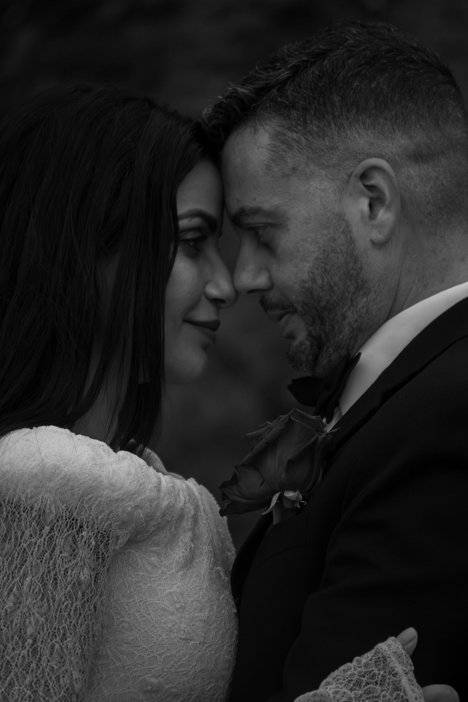 Black and white portrait of a bride and groom touching foreheads tenderly on their wedding day.