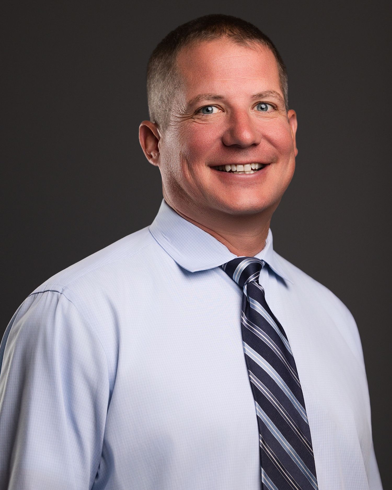 Corporate headshots showing striped tie and white dress shirt against dark backdrop.