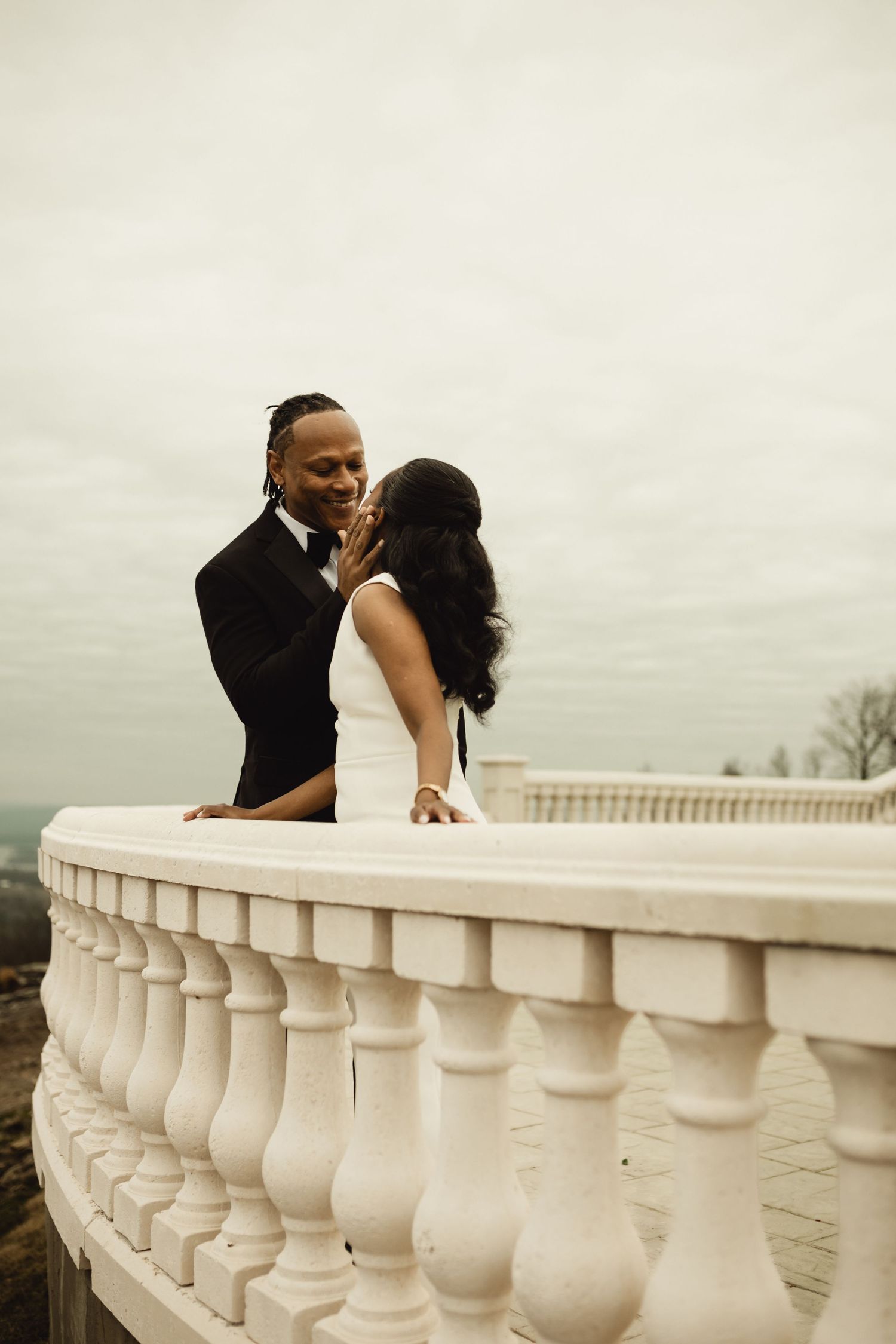 Romantic moment captured on a grand terrace with white stone balustrade.