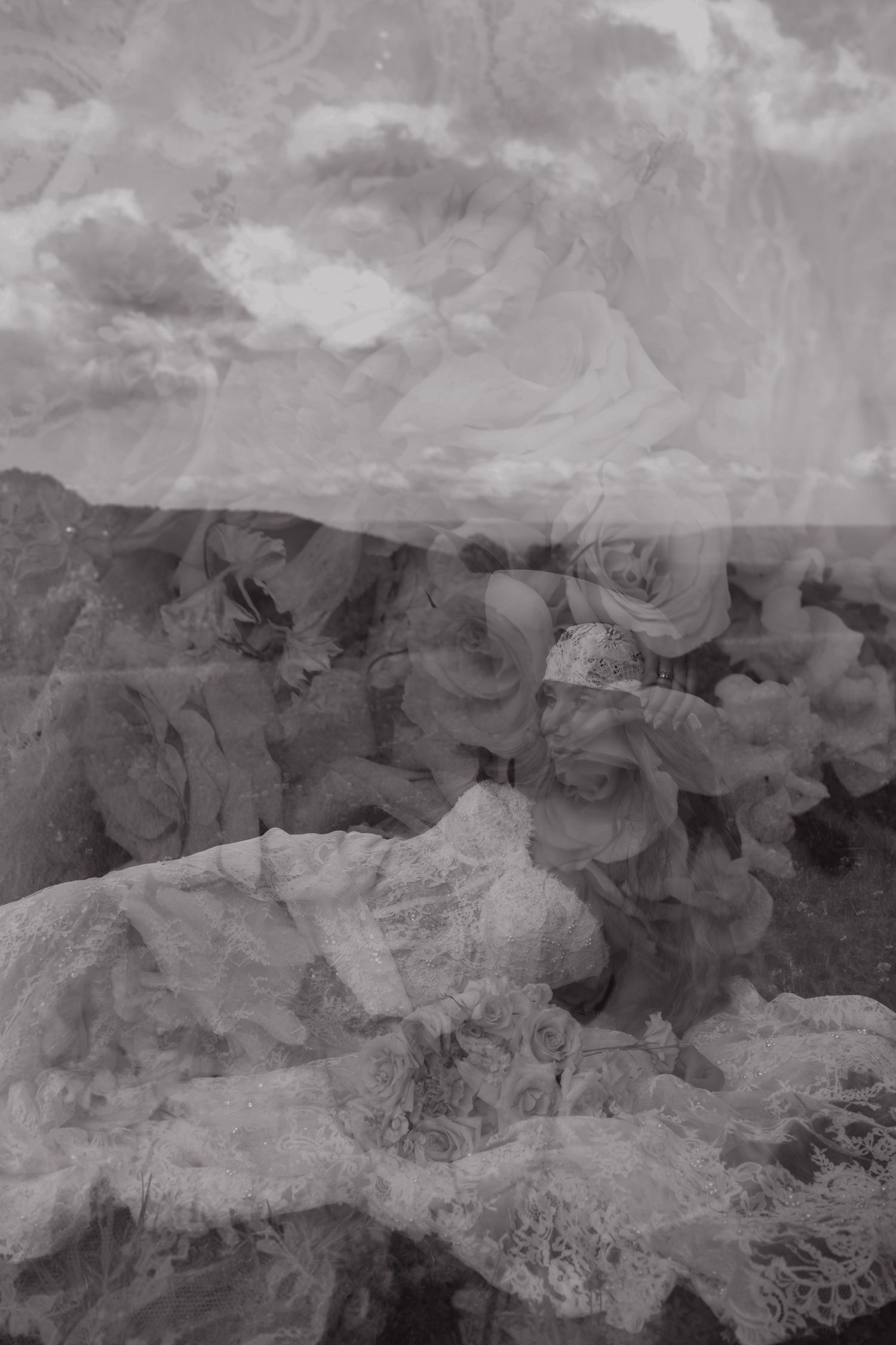 Black and white double exposure photo blending roses and dramatic cloudy landscape scenery.