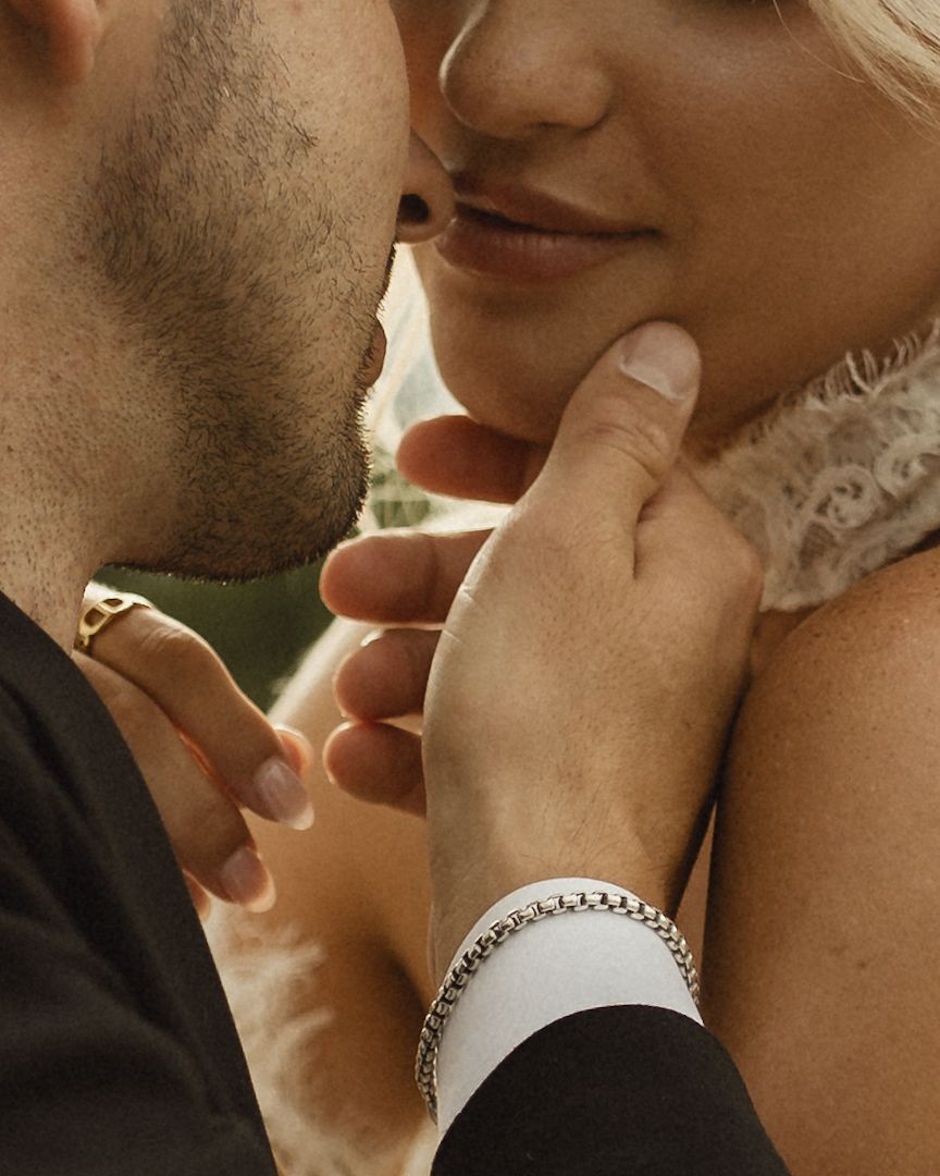 Close-up of a romantic couple almost kissing, man wearing a gold ring and woman wearing a silver bracelet.