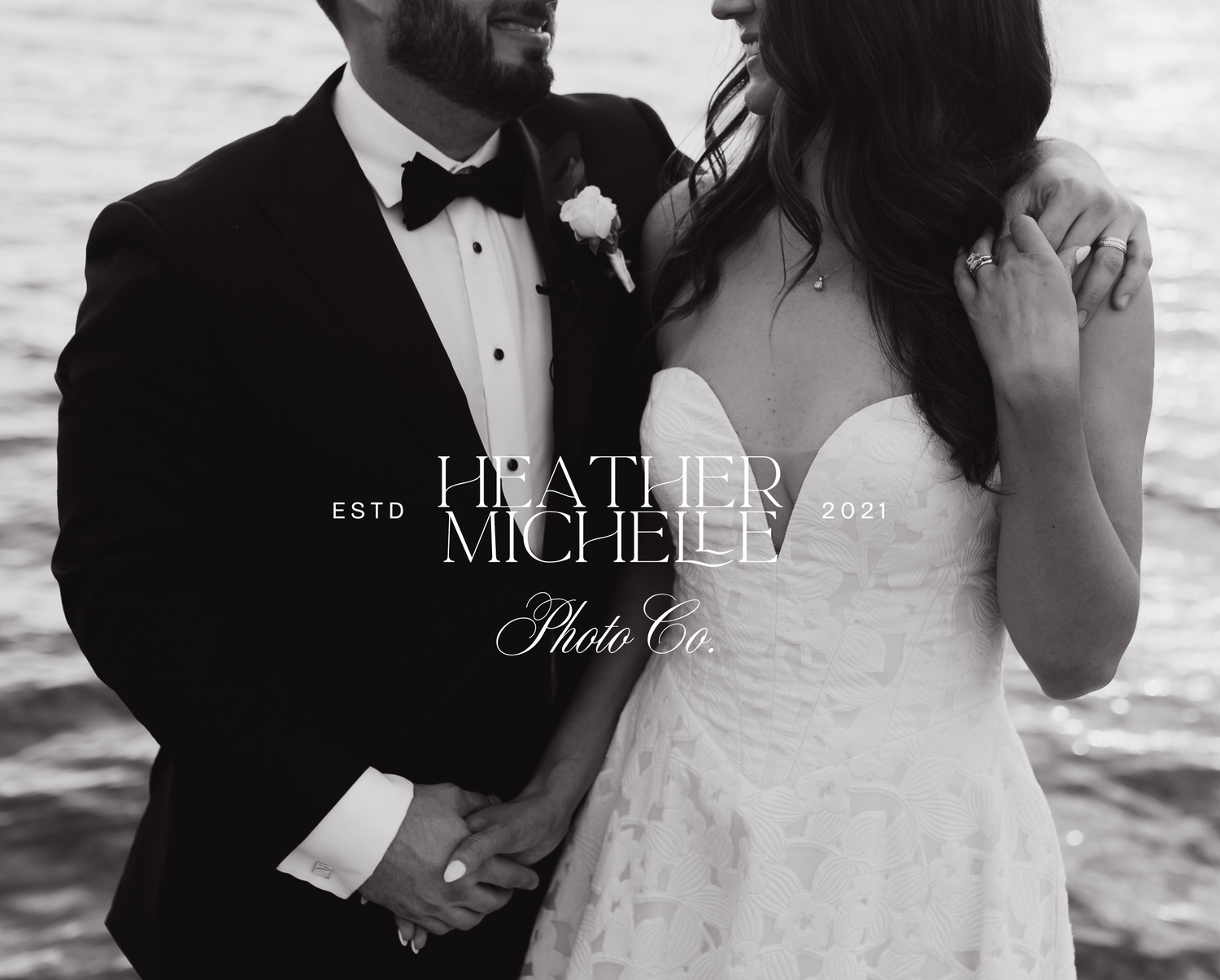 Black and white wedding photo of bride and groom holding hands, waterfront backdrop, Heather Michelle Photo Co.