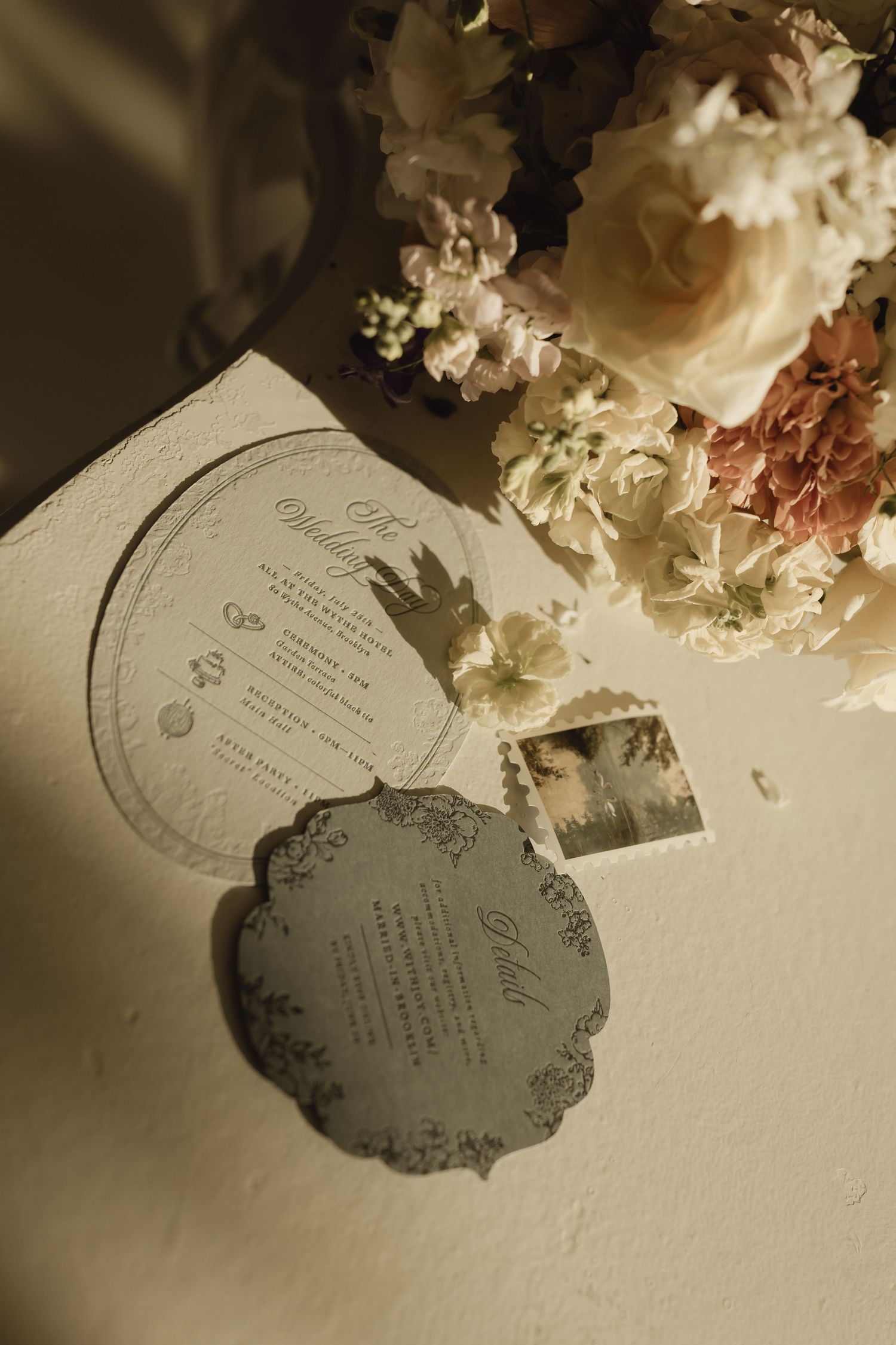 Elegant wedding stationery suite with ornate gray menu cards beside a romantic bouquet of blush and white flowers.