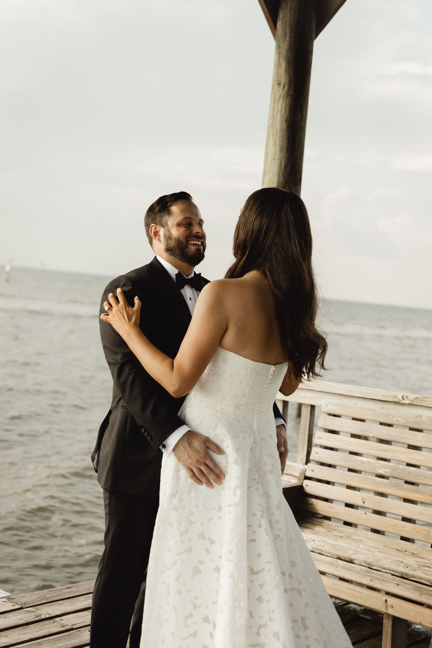 Emotional first look sequence between newlyweds on a waterfront deck.