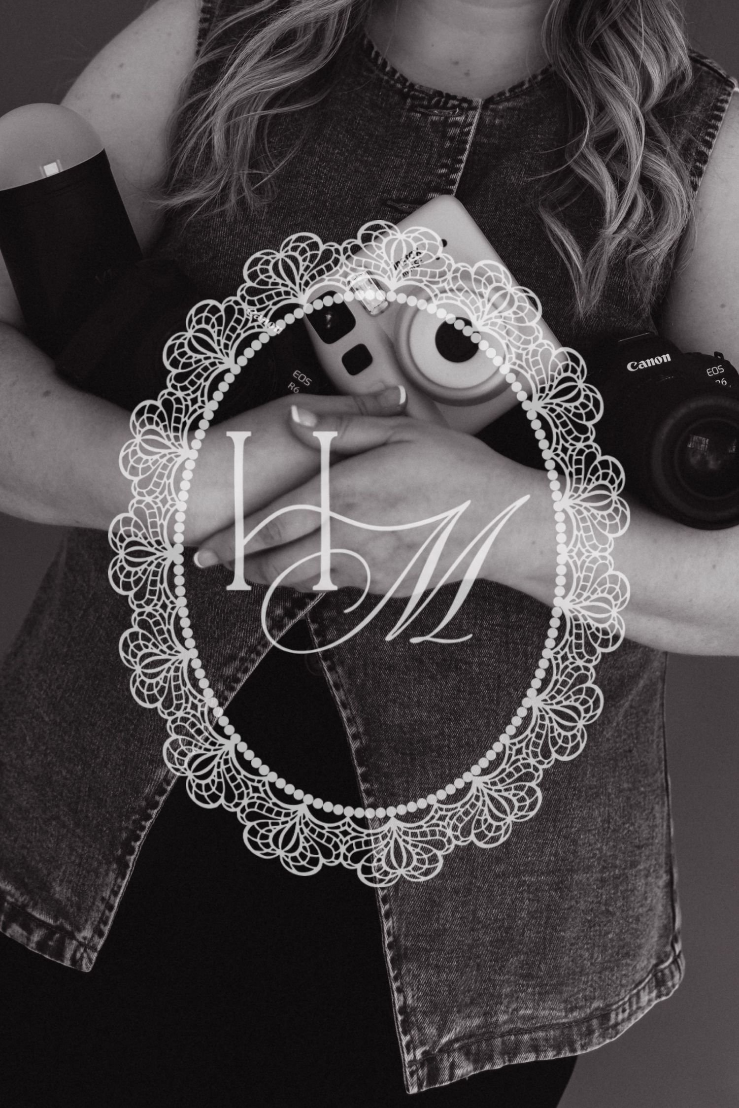Black and white photo of a woman holding a Canon camera and Instax, with an elegant lace monogram HM watermark overlay.